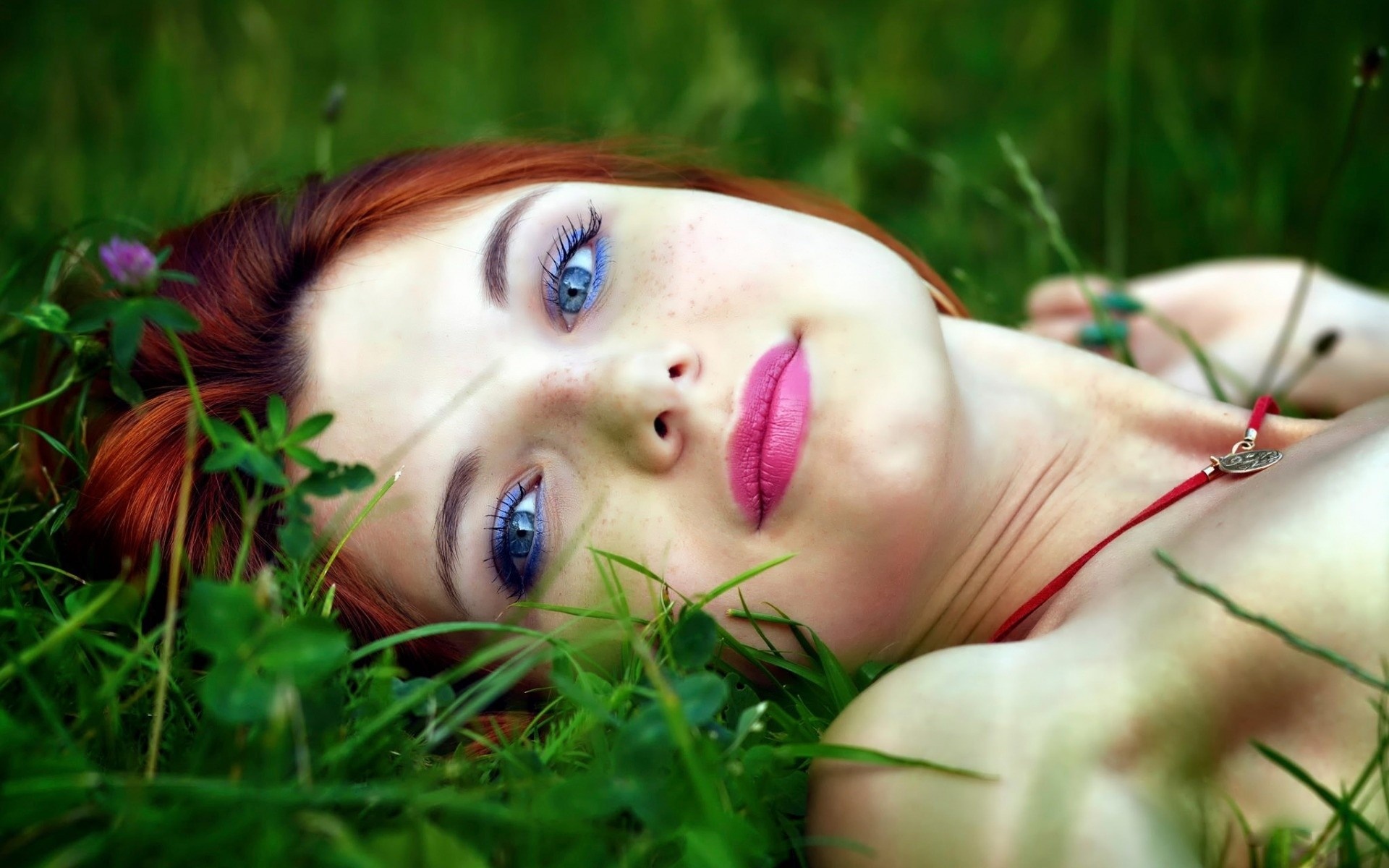 Woman with red hair and blue eyes lying in grass HD Wallpaper