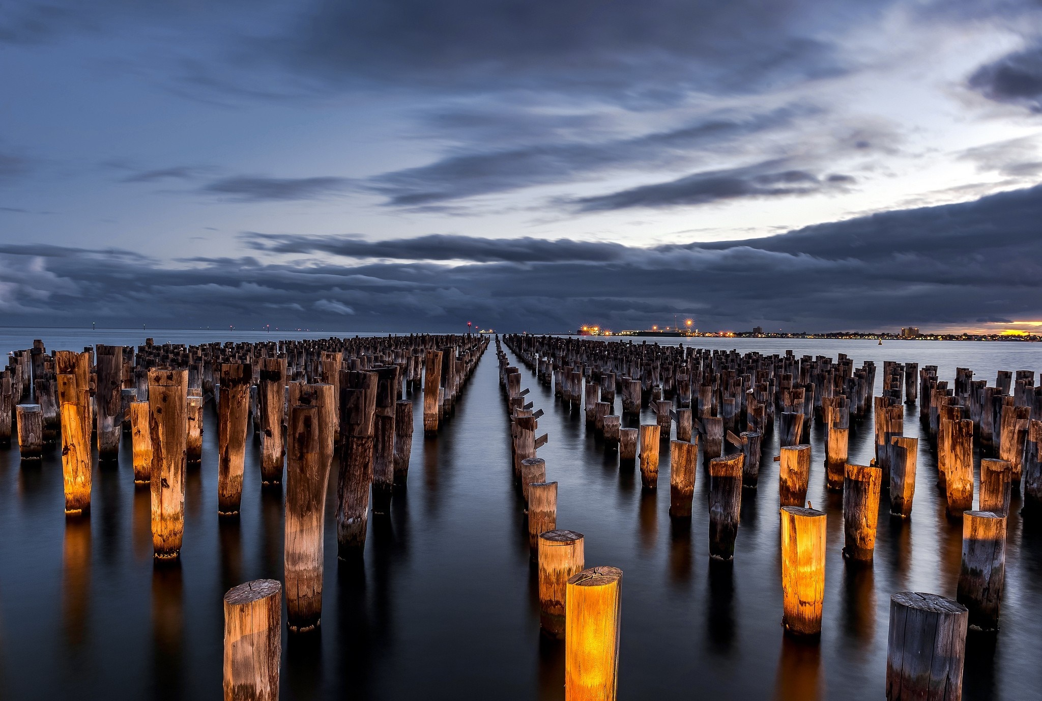 Wooden pier pilings in the ocean at dusk HD Wallpaper