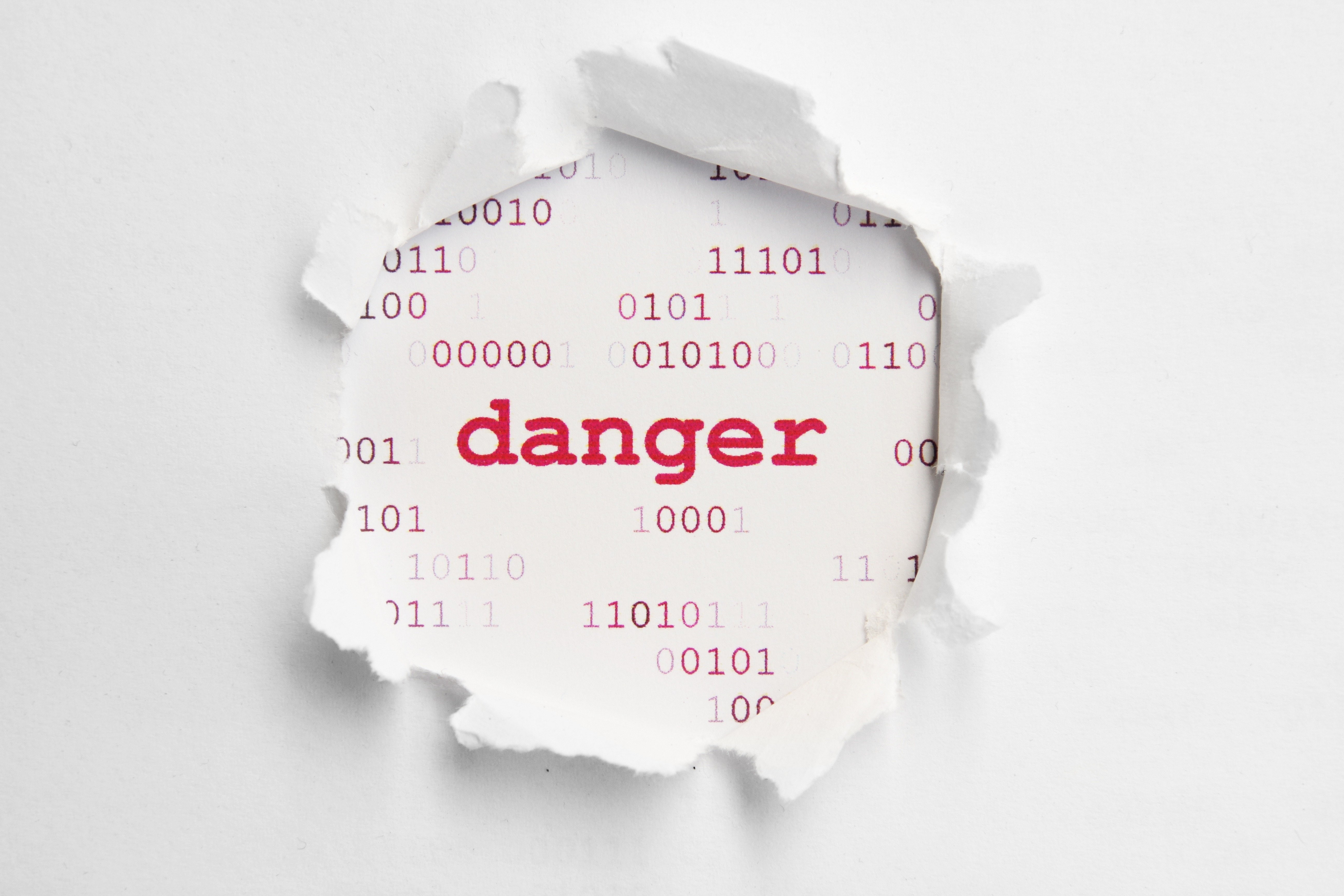 Torn paper revealing "danger" text and binary code HD Wallpaper