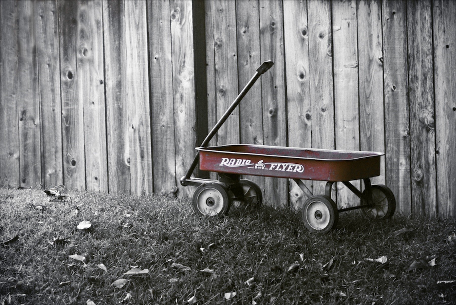 Red Radio Flyer wagon by a wooden fence HD Wallpaper