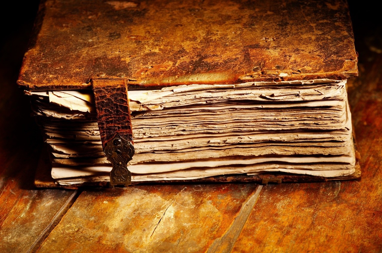 Old leather-bound book on a wooden table HD Wallpaper