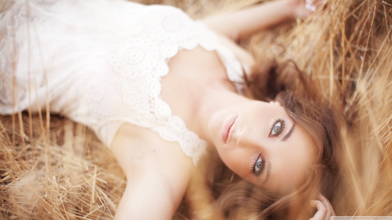Woman lying in dry grass wearing a white lace dress HD Wallpaper