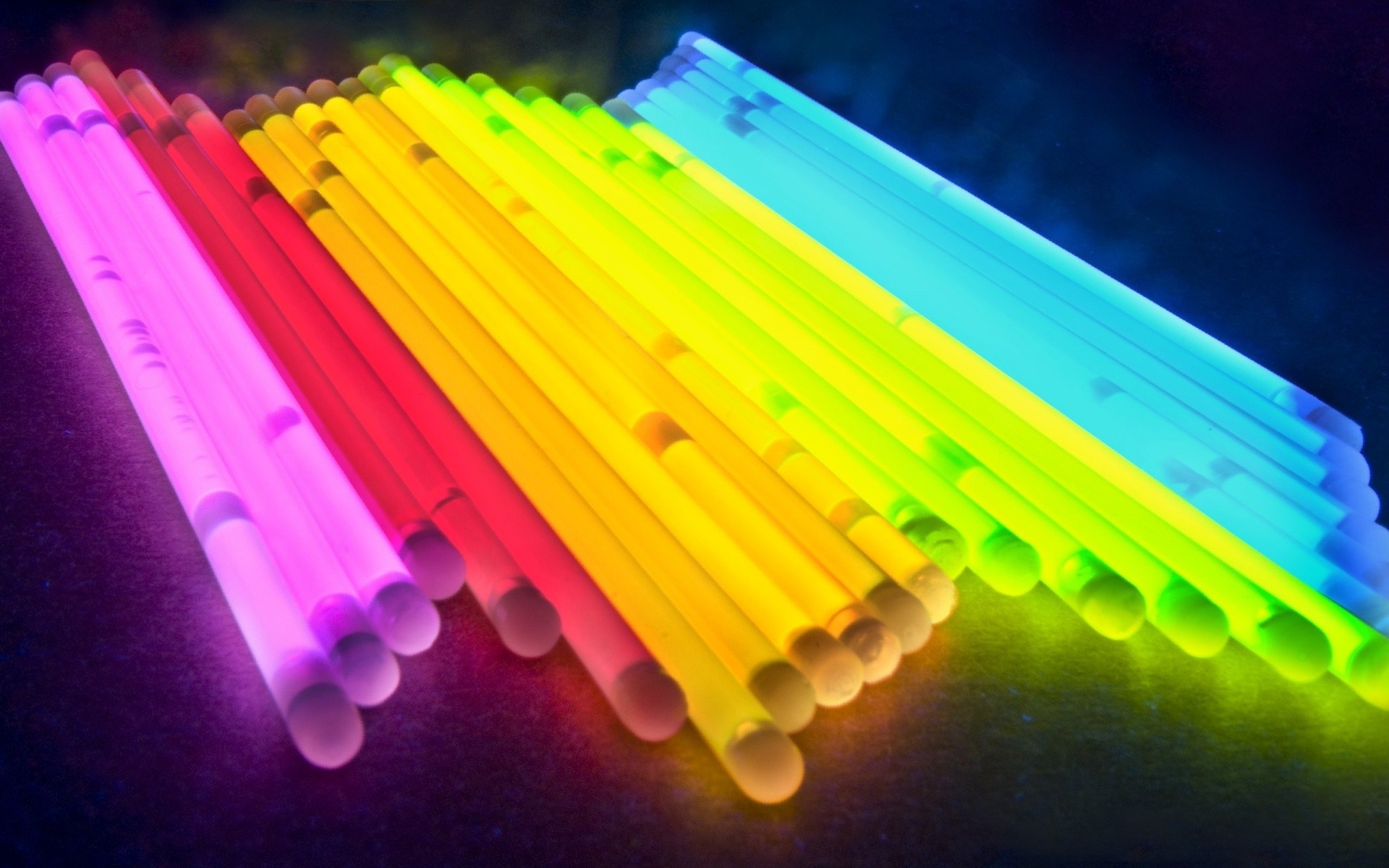 Colorful glow sticks arranged in a rainbow pattern HD Wallpaper