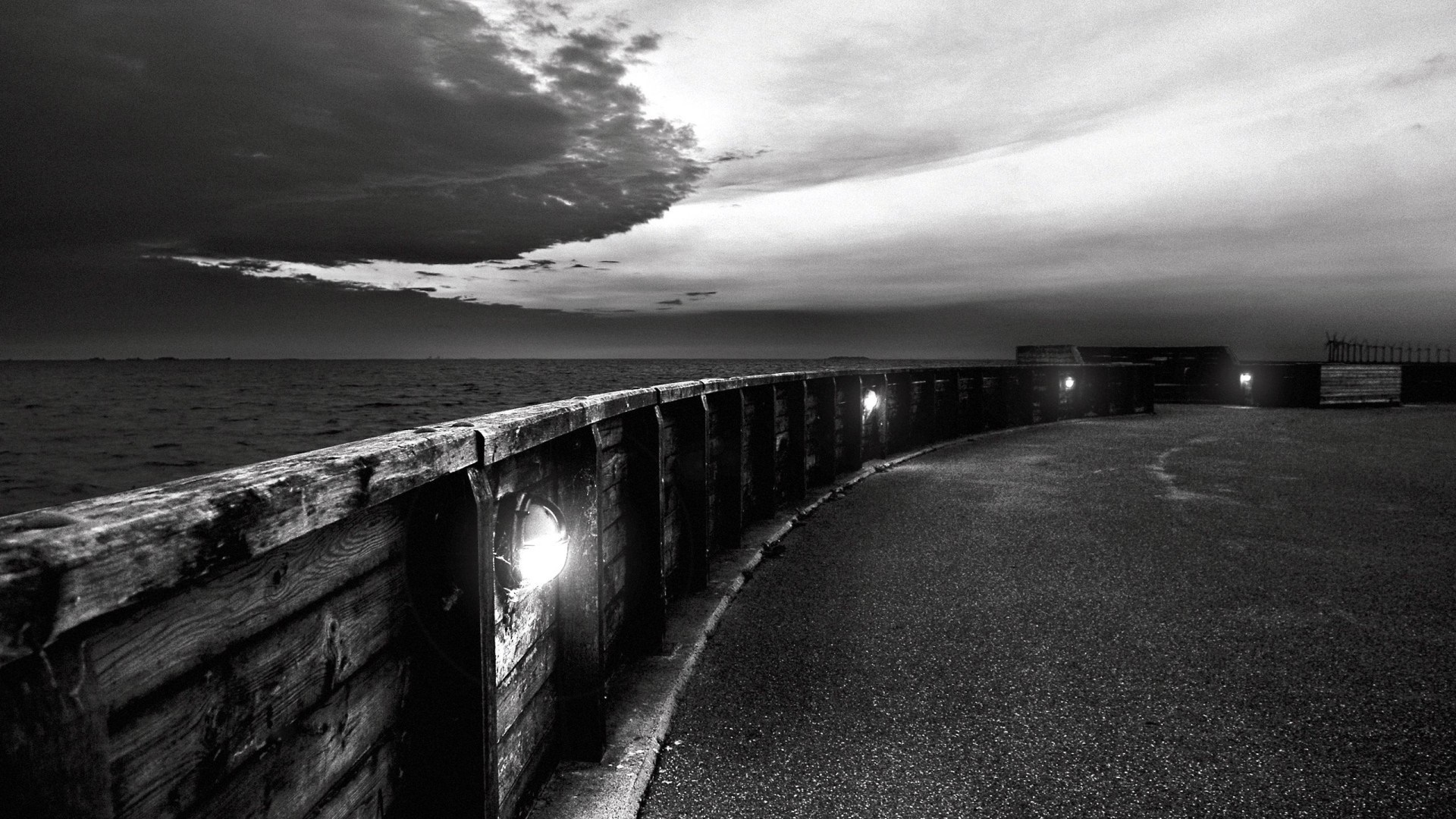 Monochrome view of a seaside promenade at dusk HD Wallpaper