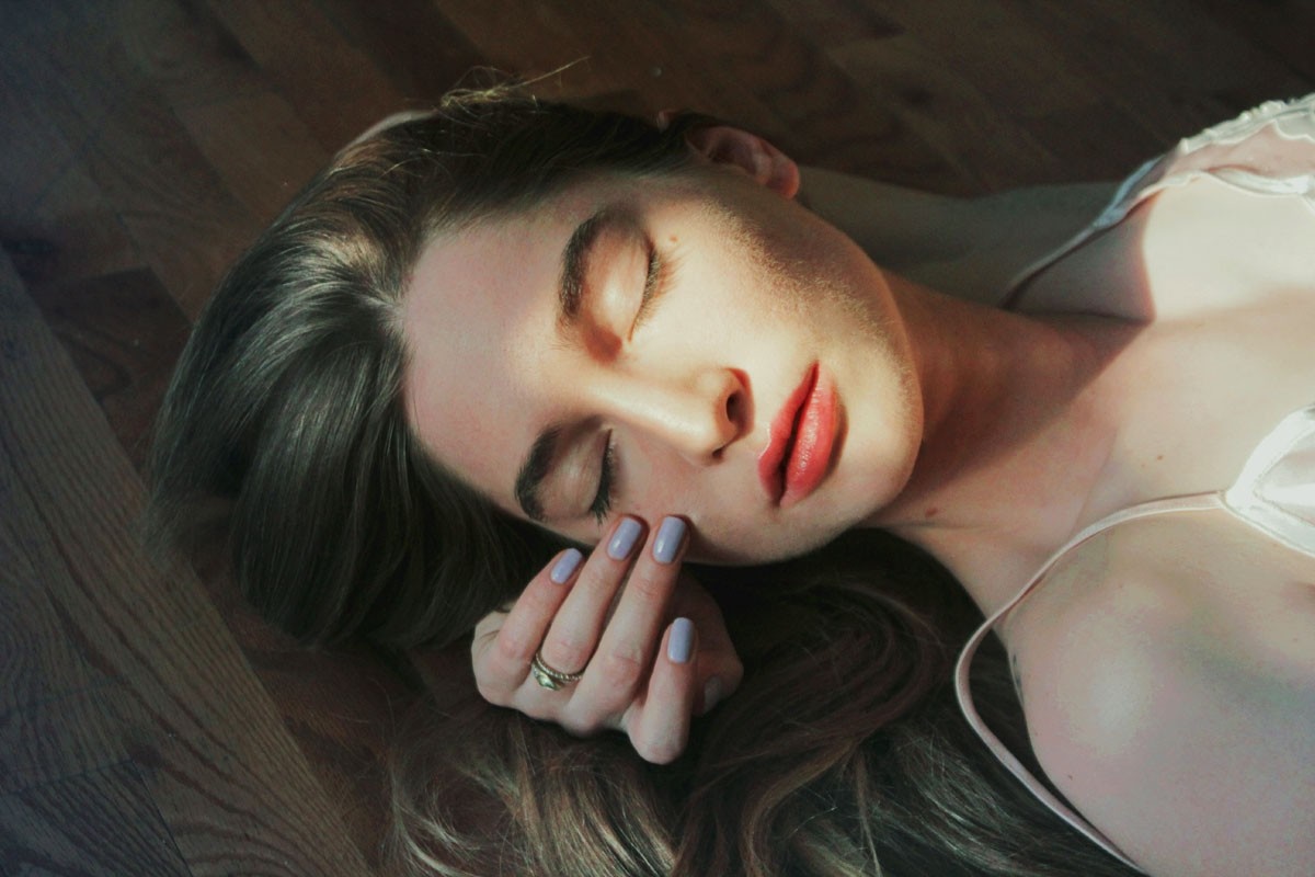 Woman with closed eyes lying on wooden floor HD Wallpaper