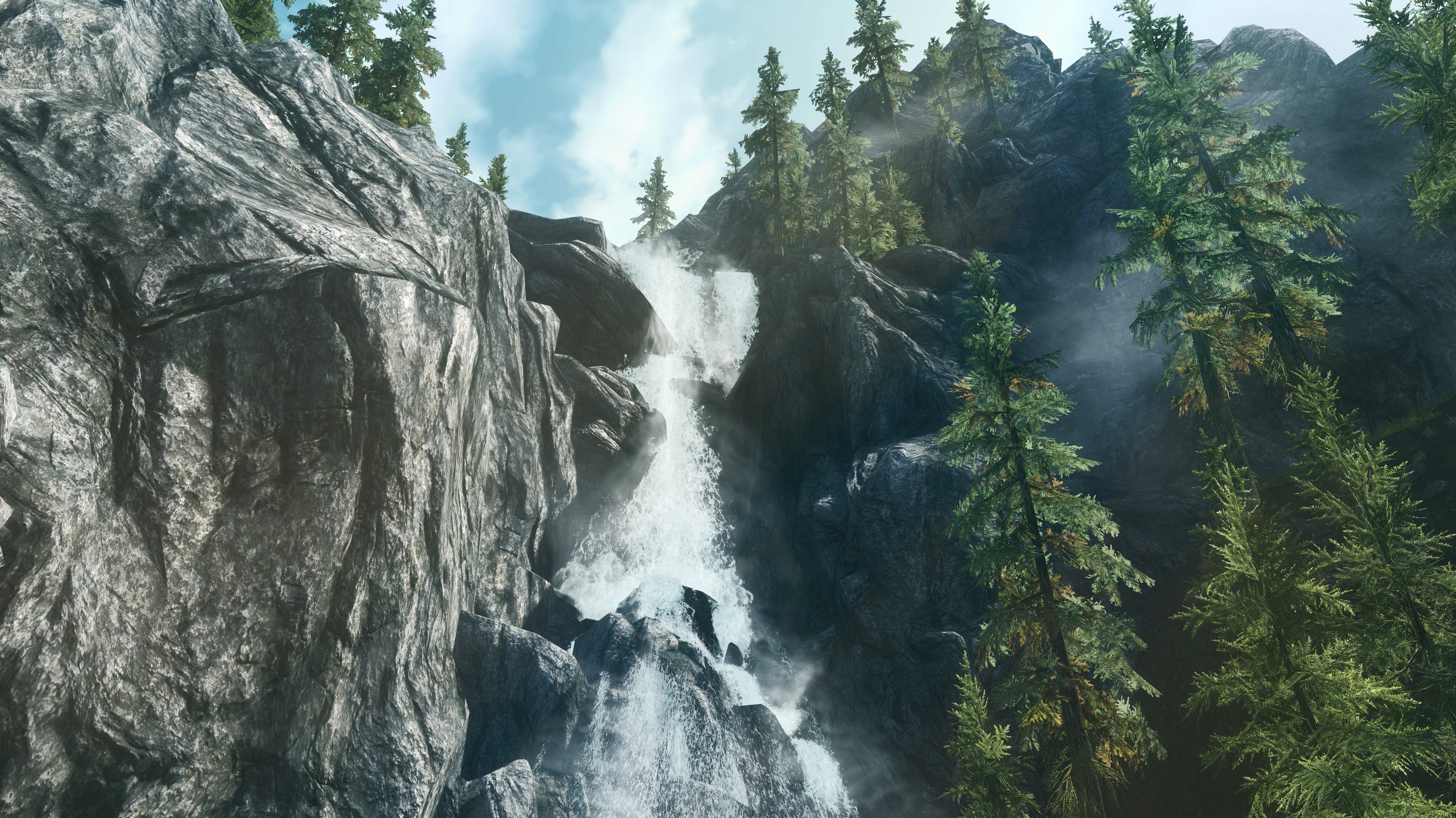 Waterfall cascading down a rocky cliff in a forest HD Wallpaper
