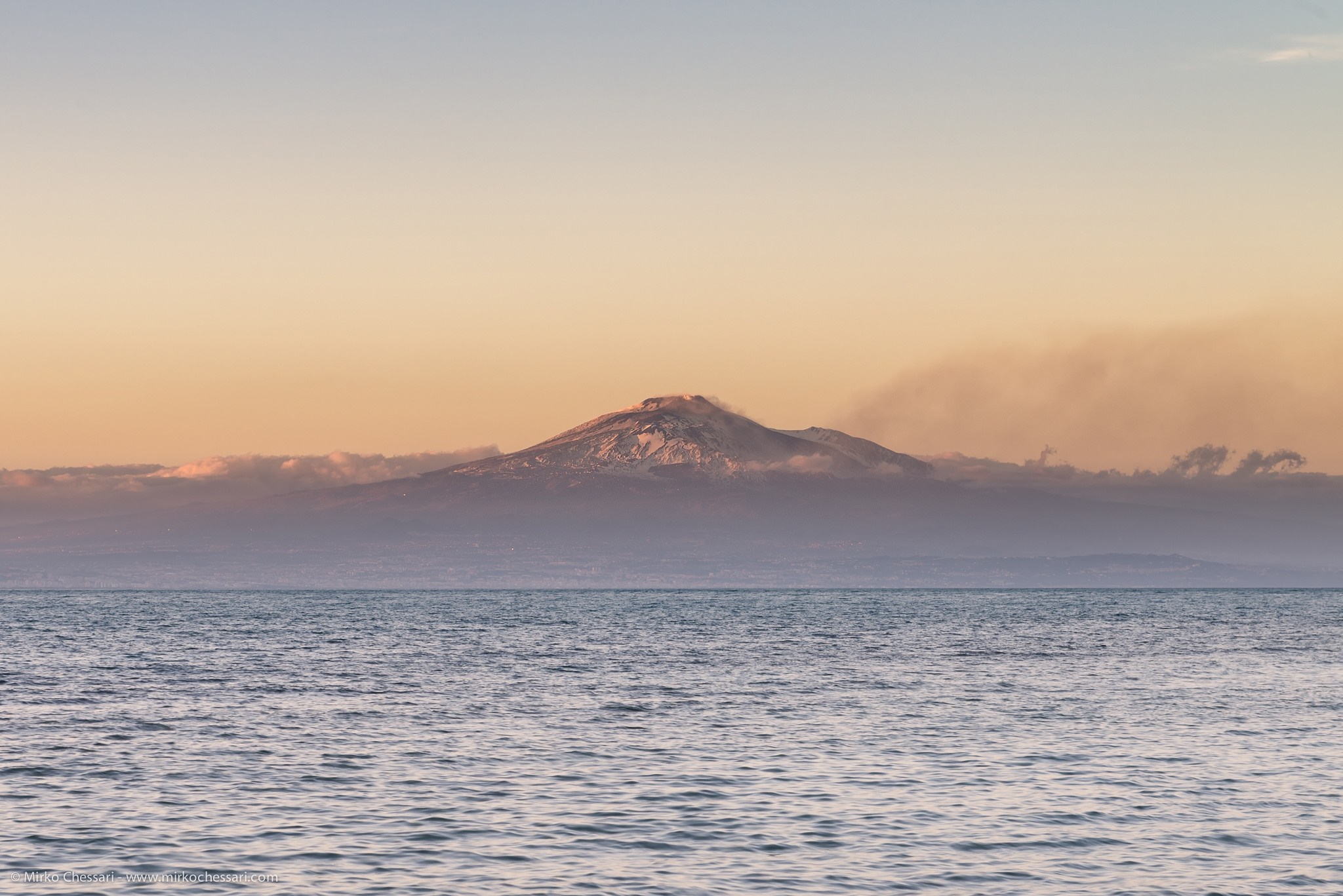 Volcano erupting smoke over the sea at sunset HD Wallpaper