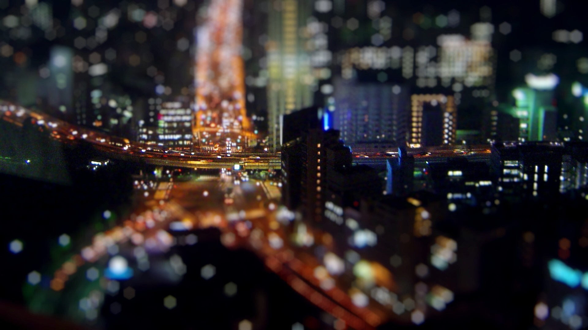 Tilt-shift cityscape at night with city lights and traffic HD Wallpaper