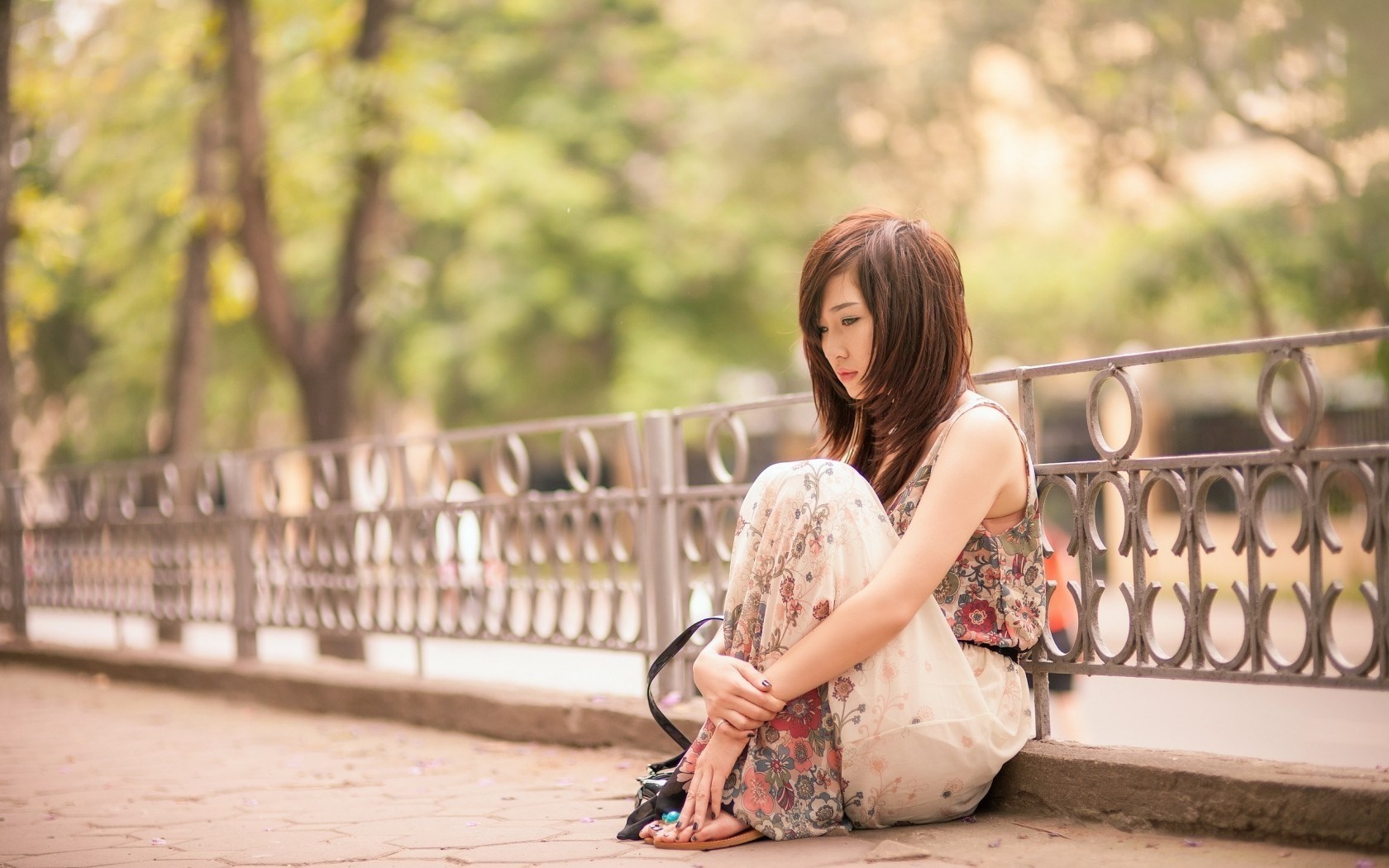 Peaceful Woman Sitting Outdoors in Floral Dress HD Wallpaper