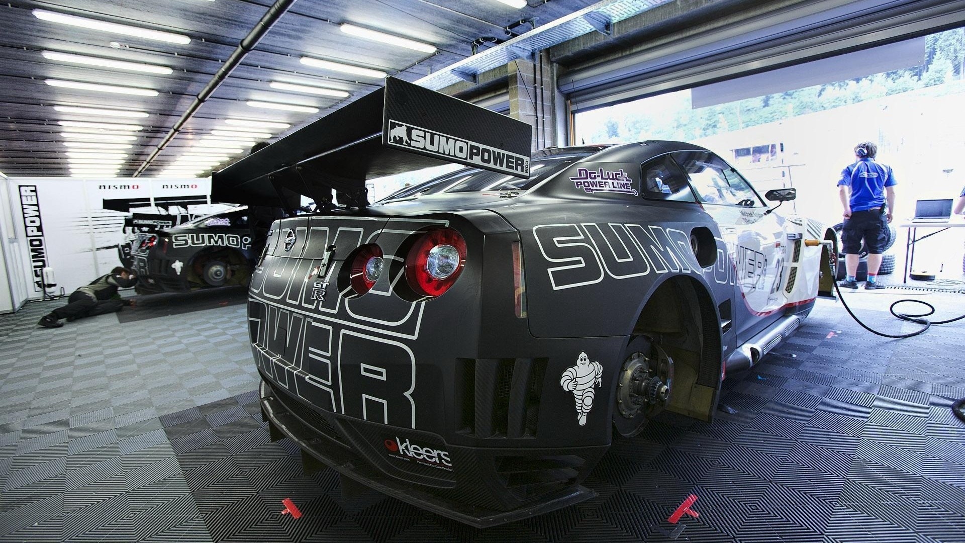 Nissan GT-R race cars in a pit garage with mechanics HD Wallpaper