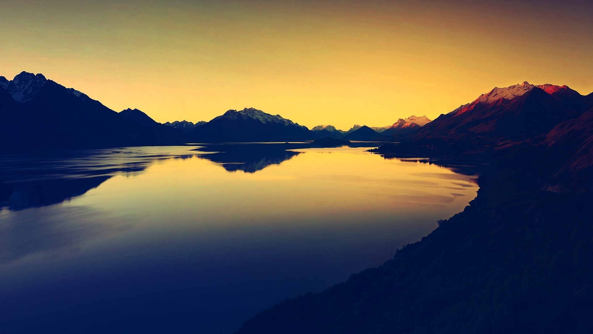 Mountain range reflected in a lake at sunset HD Wallpaper