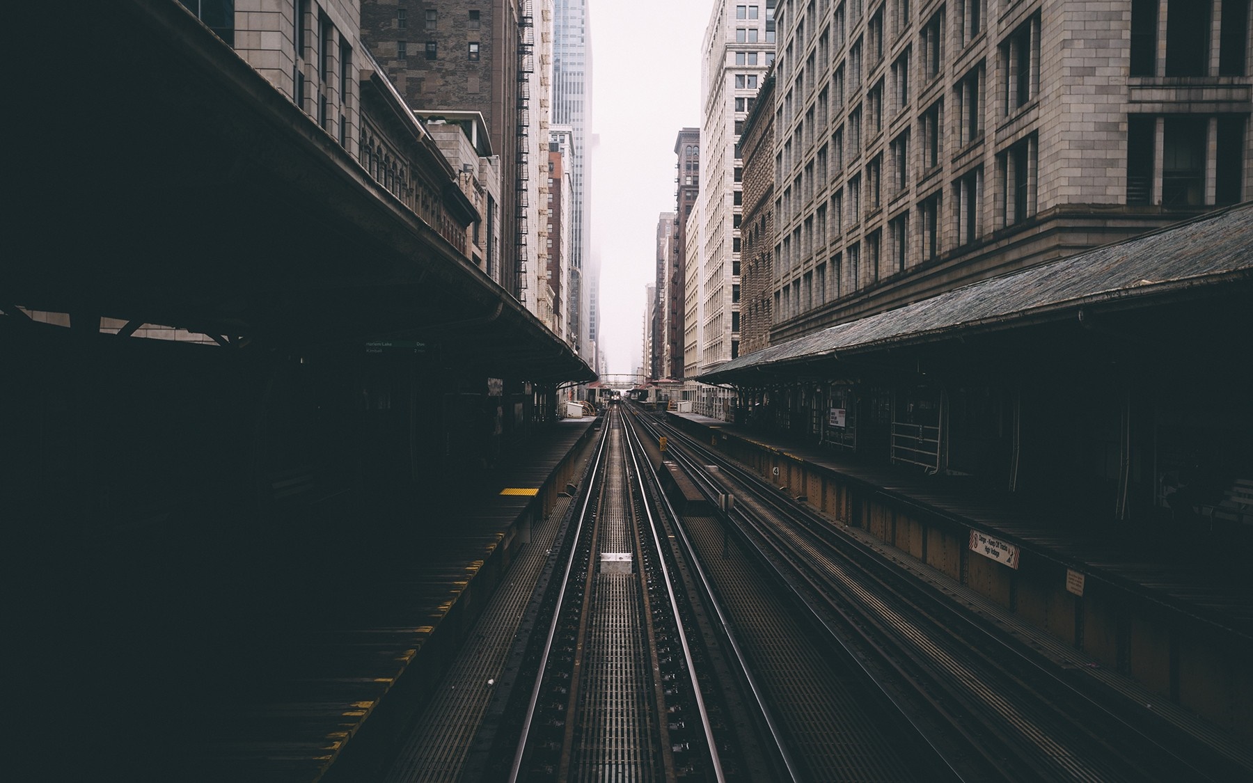 Train tracks between city buildings and platforms HD Wallpaper