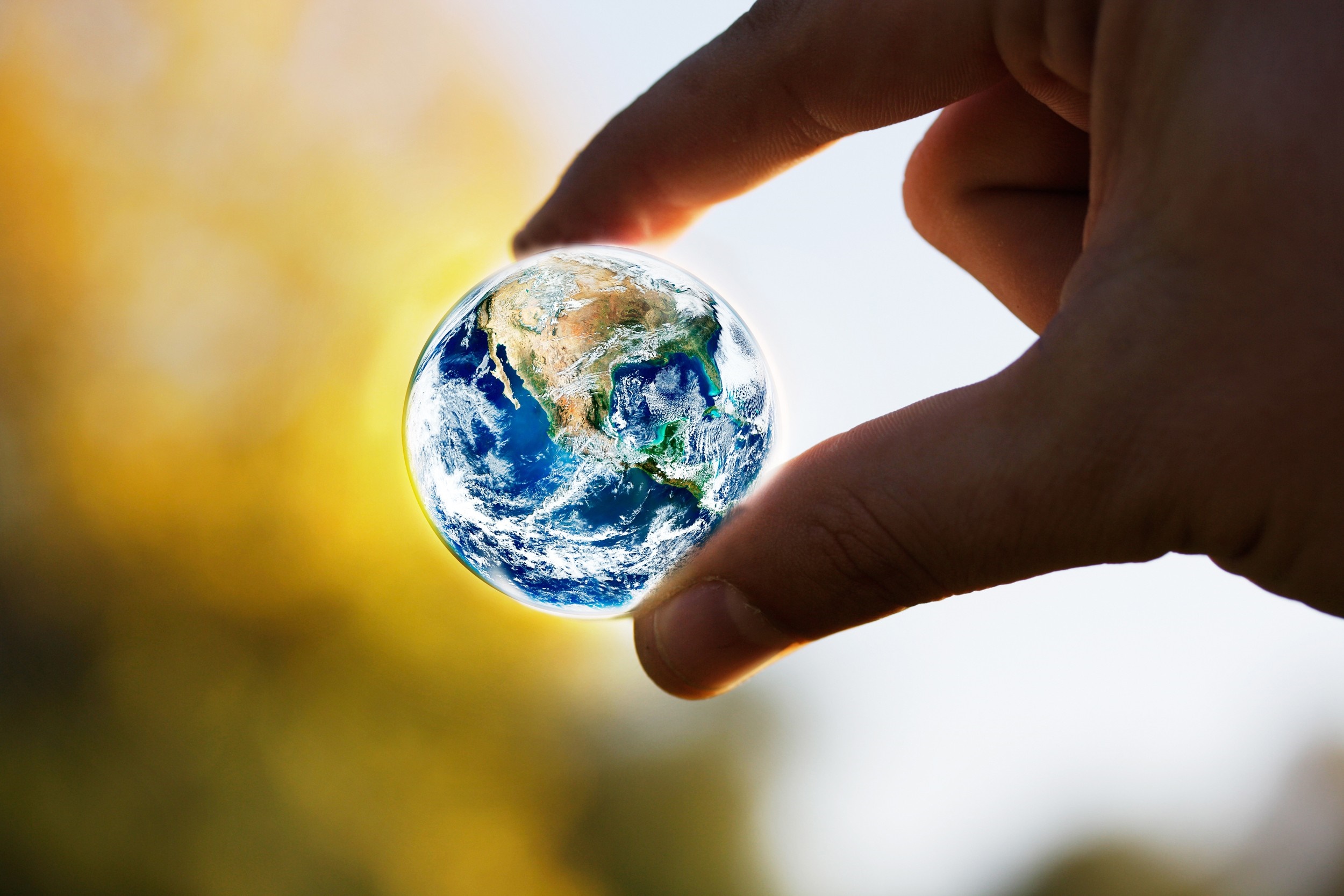 Hand holding a miniature Earth globe HD Wallpaper