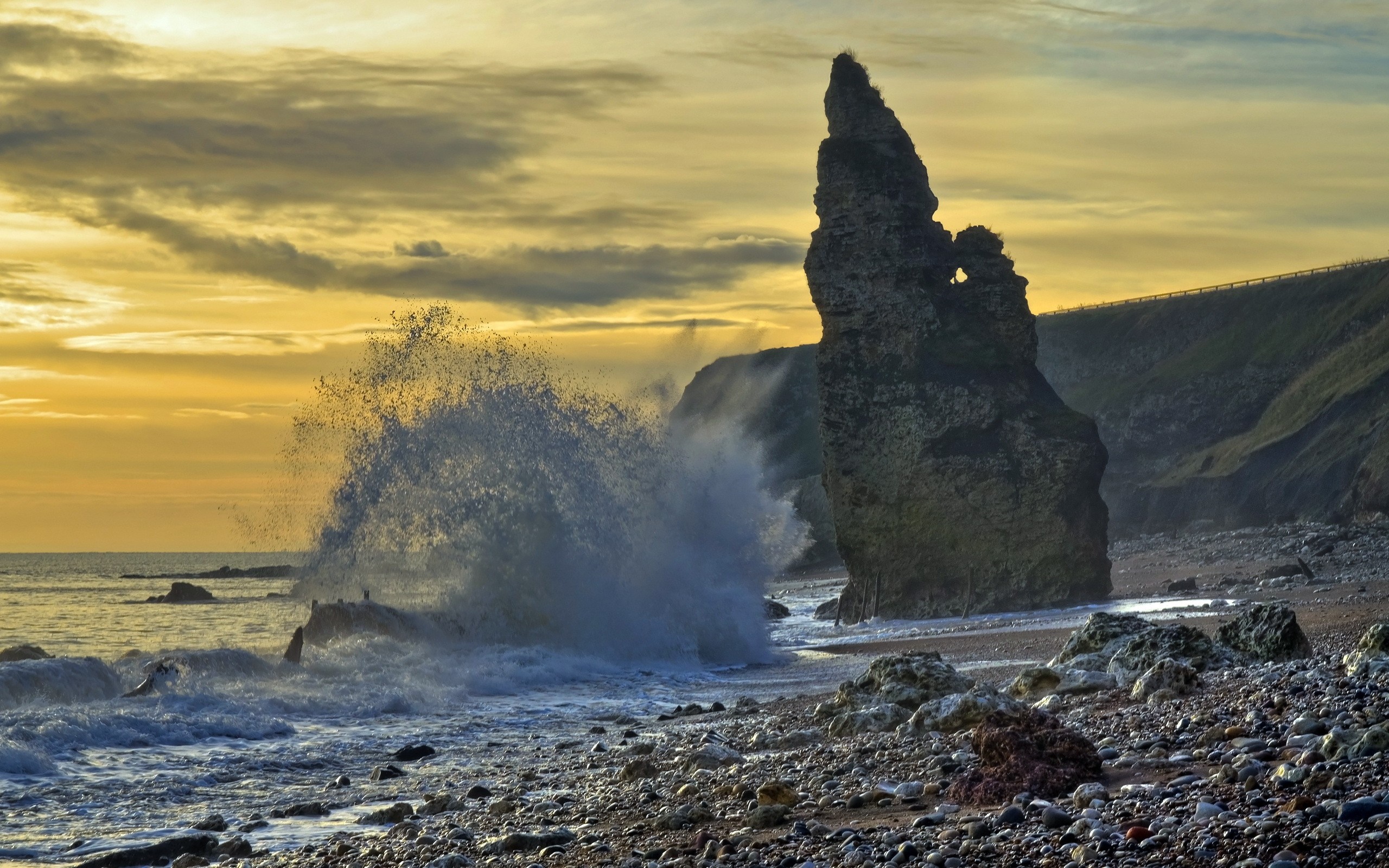Wave crashing on a rocky shore at sunset HD Wallpaper