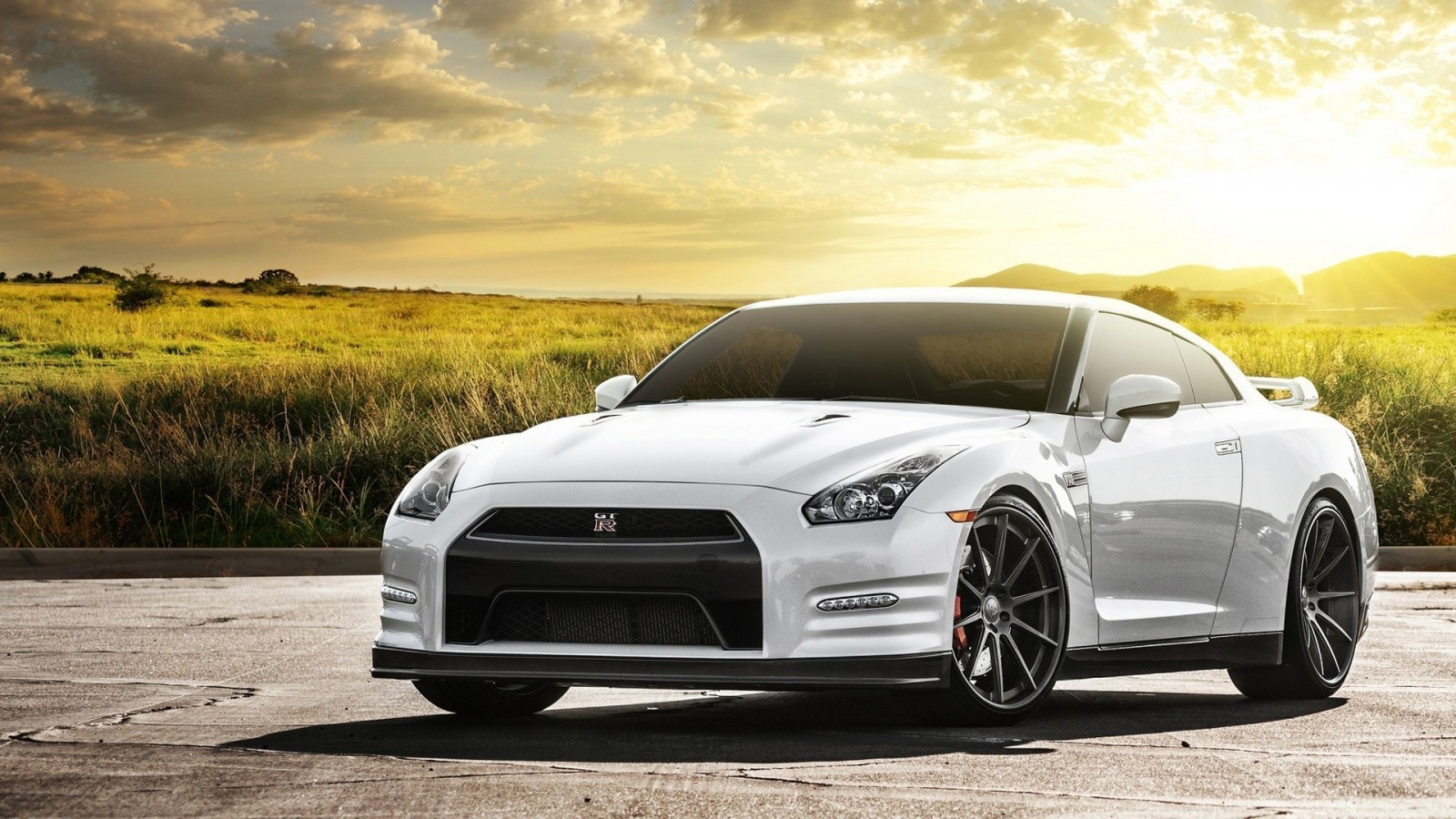 White Nissan GT-R parked on asphalt with field background HD Wallpaper