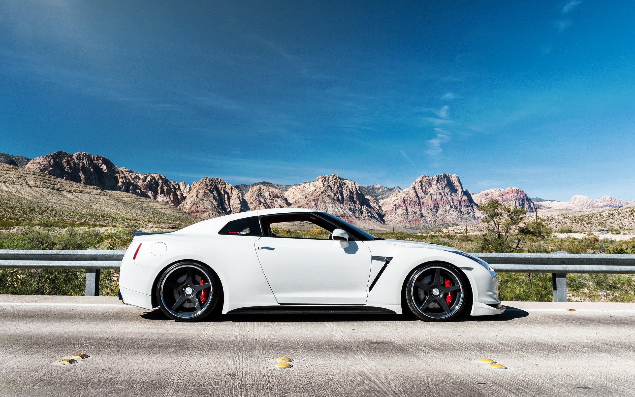 White Nissan GT-R parked on a road with mountains HD Wallpaper