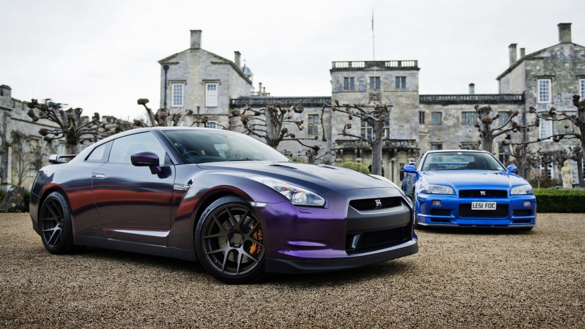 Two Nissan GT-R cars parked in front of a building HD Wallpaper