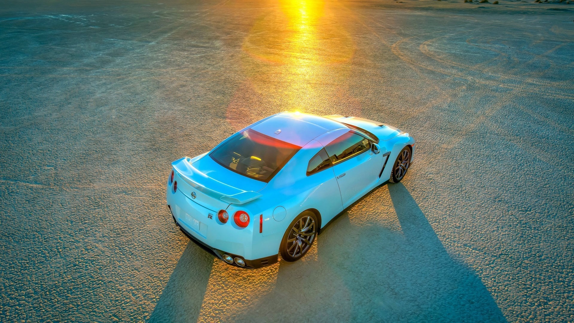 White Nissan GT-R on a dry lake bed at sunset HD Wallpaper