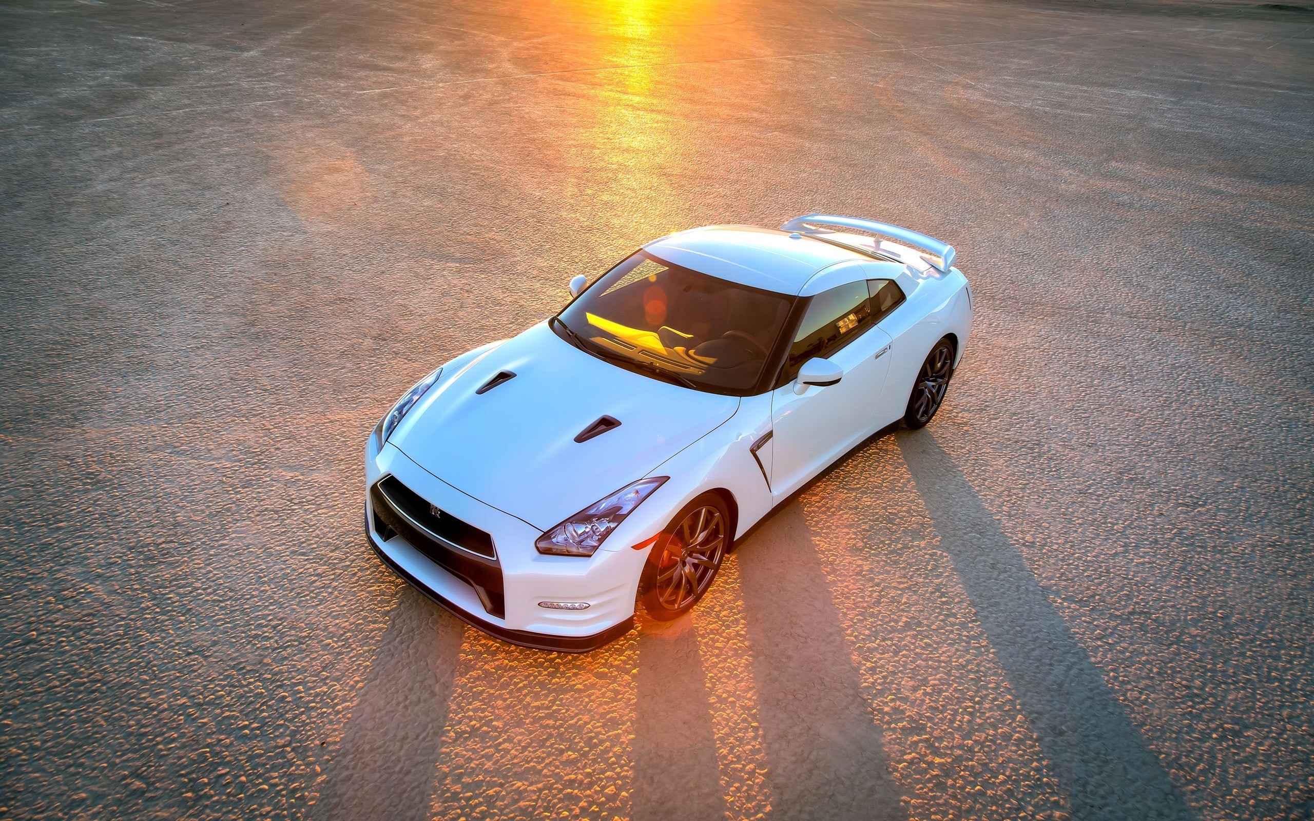 White Nissan GT-R sports car on a dry surface at sunset HD Wallpaper