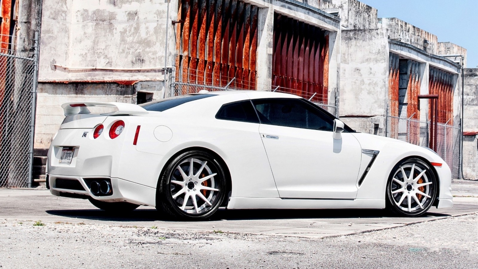 White Nissan GT-R parked near a weathered building HD Wallpaper