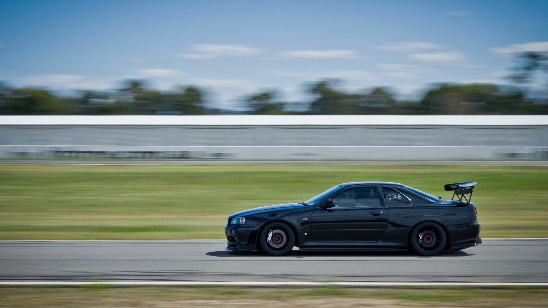 Black Nissan Skyline GT-R R34 on a Racetrack HD Wallpaper
