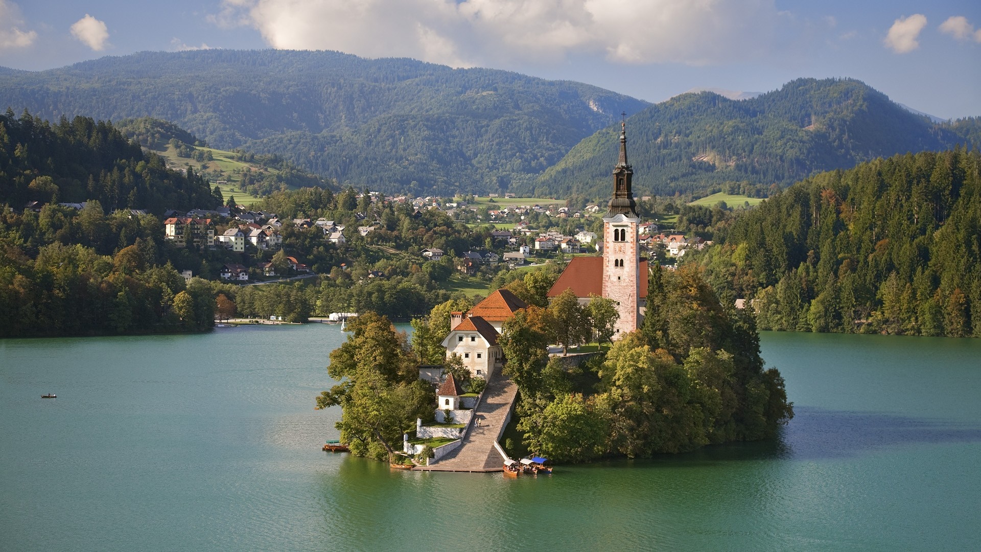 Island church on a lake with mountains and a village HD Wallpaper