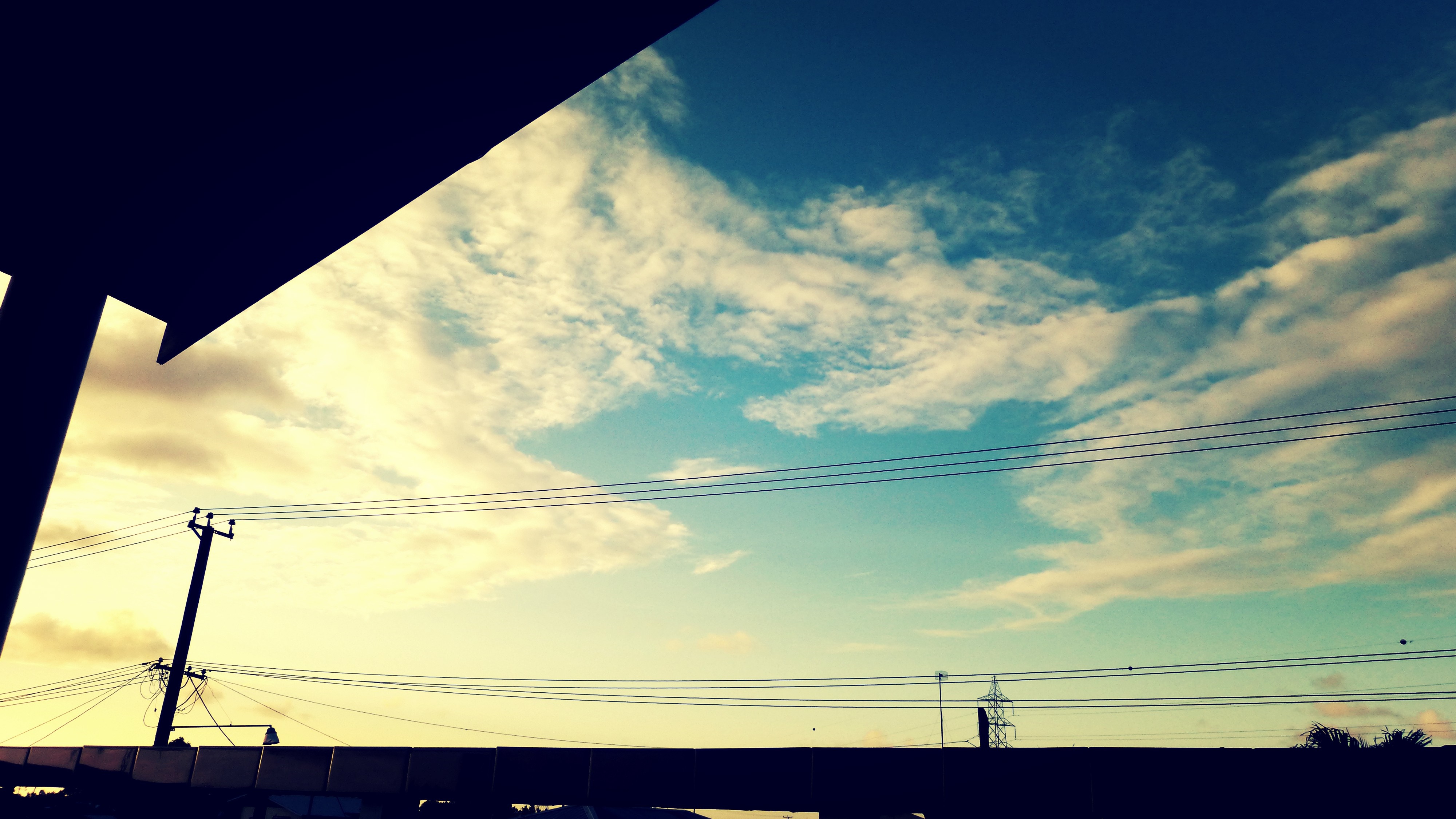 Silhouette of power lines and structures against a cloudy sky HD Wallpaper