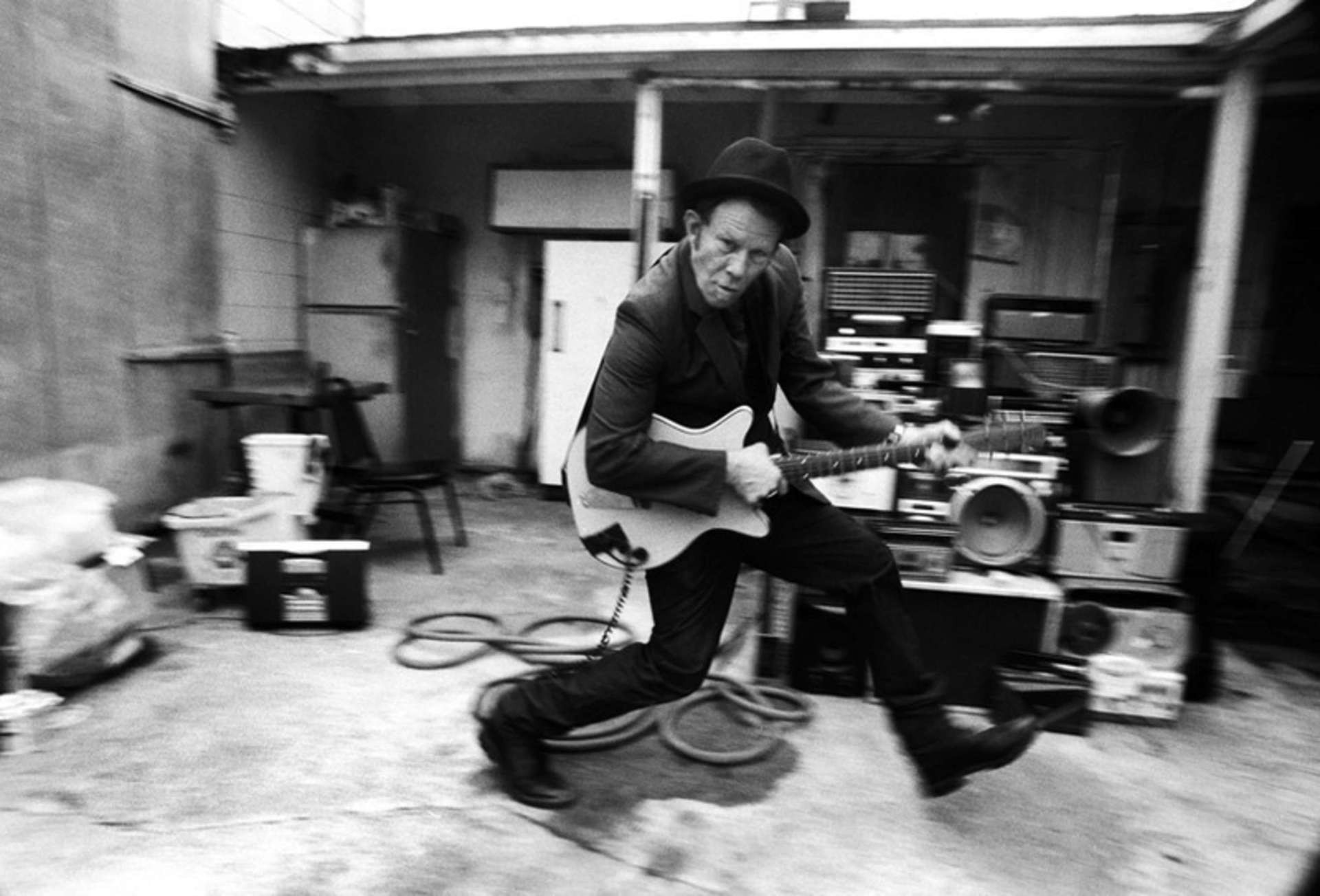 Tom Waits playing guitar in a backyard HD Wallpaper