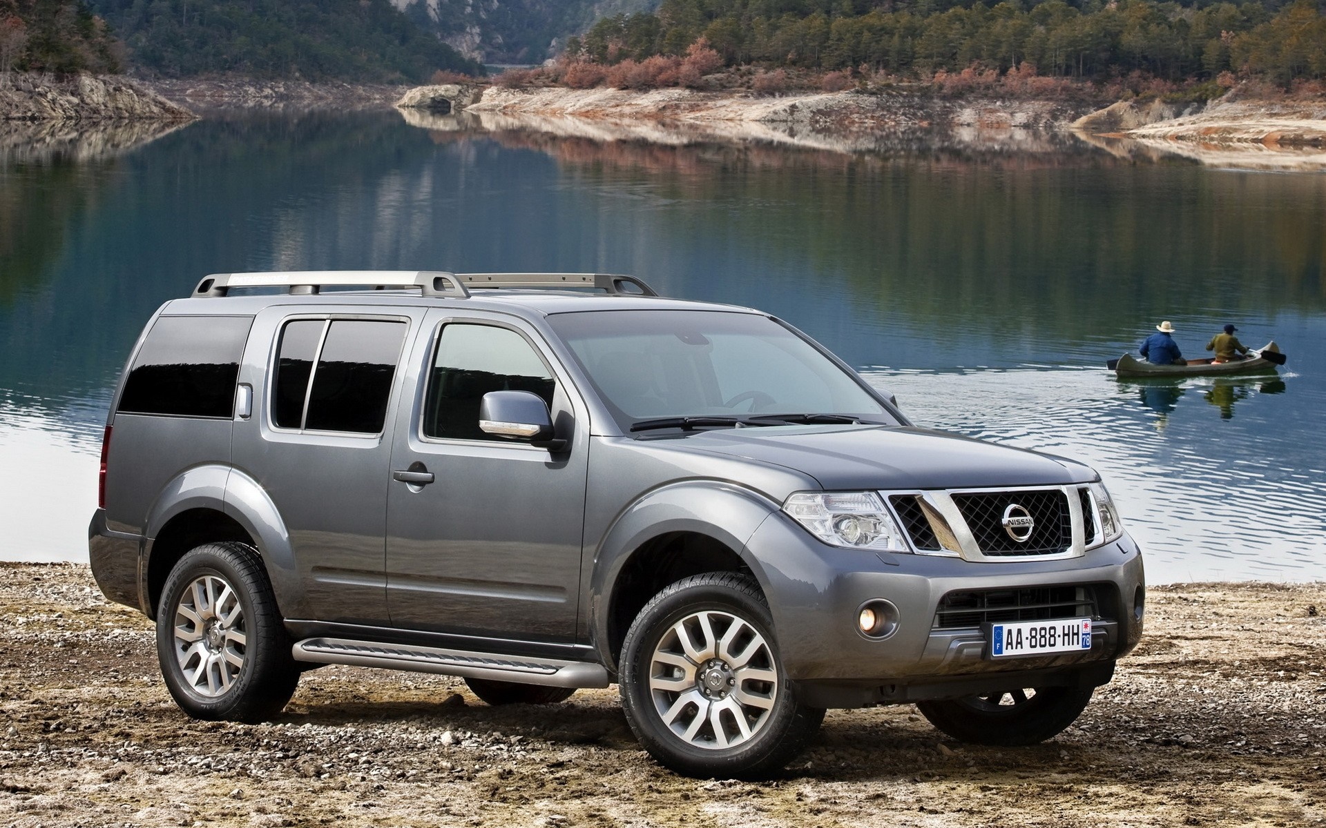 Nissan Pathfinder SUV by a lake with people in a canoe HD Wallpaper