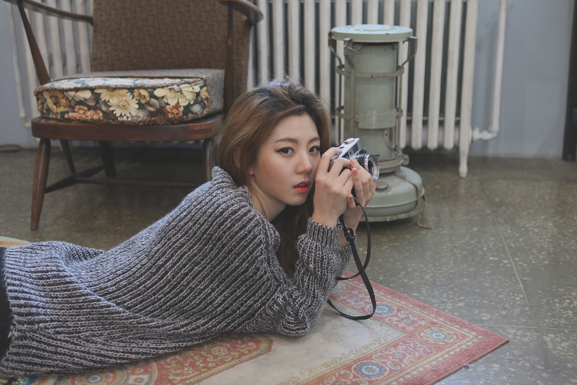 Woman holding a camera, lying on a rug HD Wallpaper