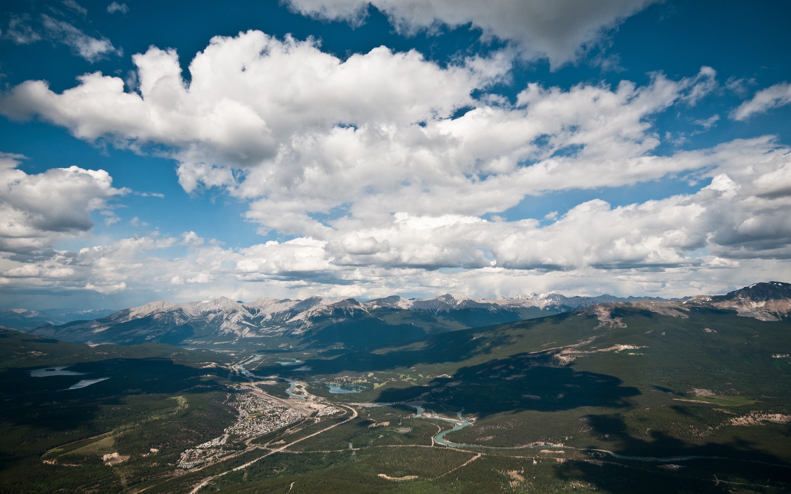 Aerial view of mountains and a town under a cloudy sky HD Wallpaper