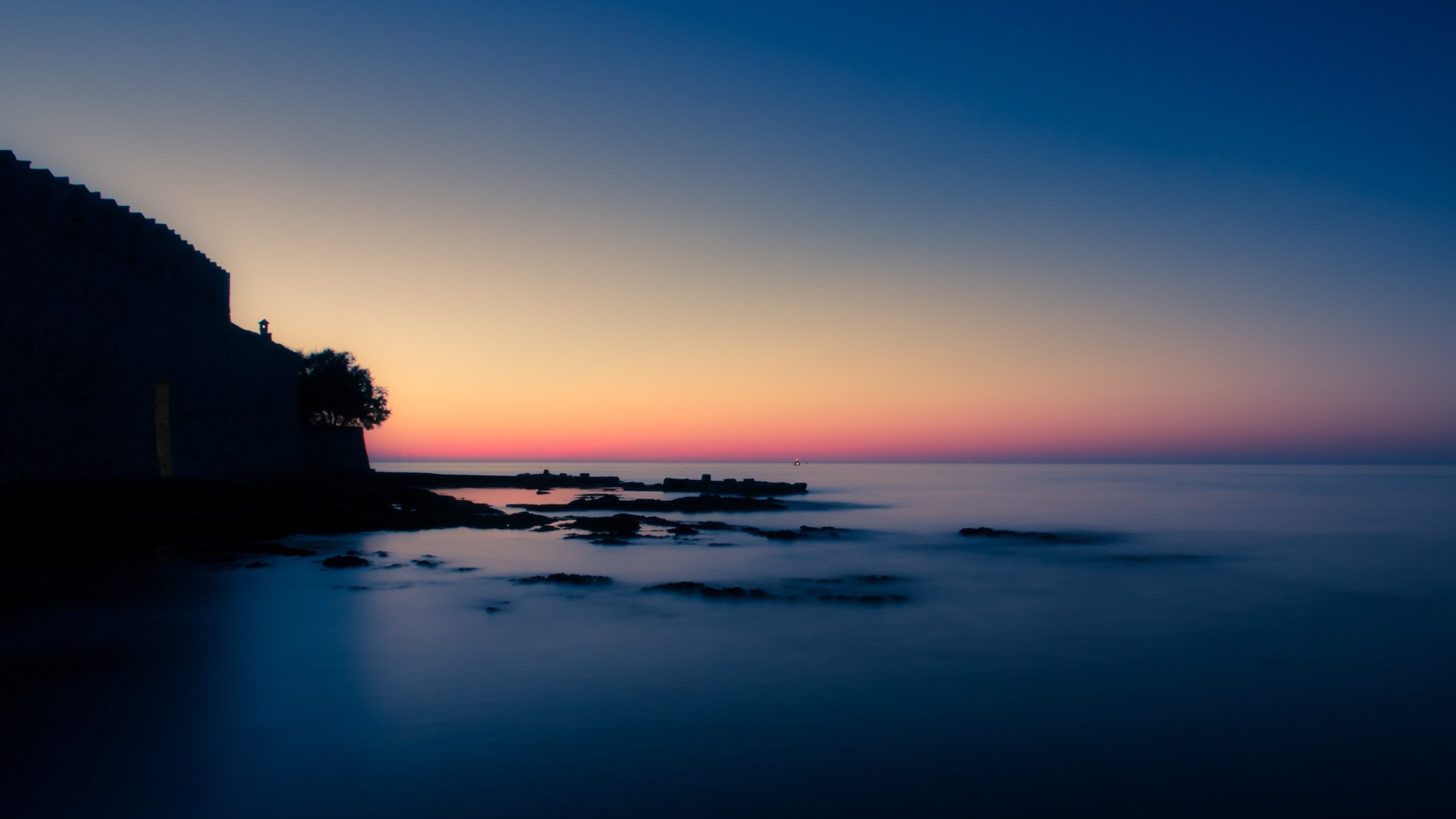 Silhouette of a castle wall by the sea at sunset HD Wallpaper