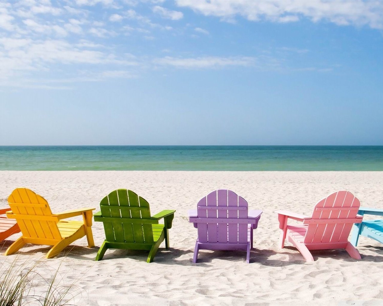 Colorful Adirondack chairs on a sandy beach by the ocean HD Wallpaper