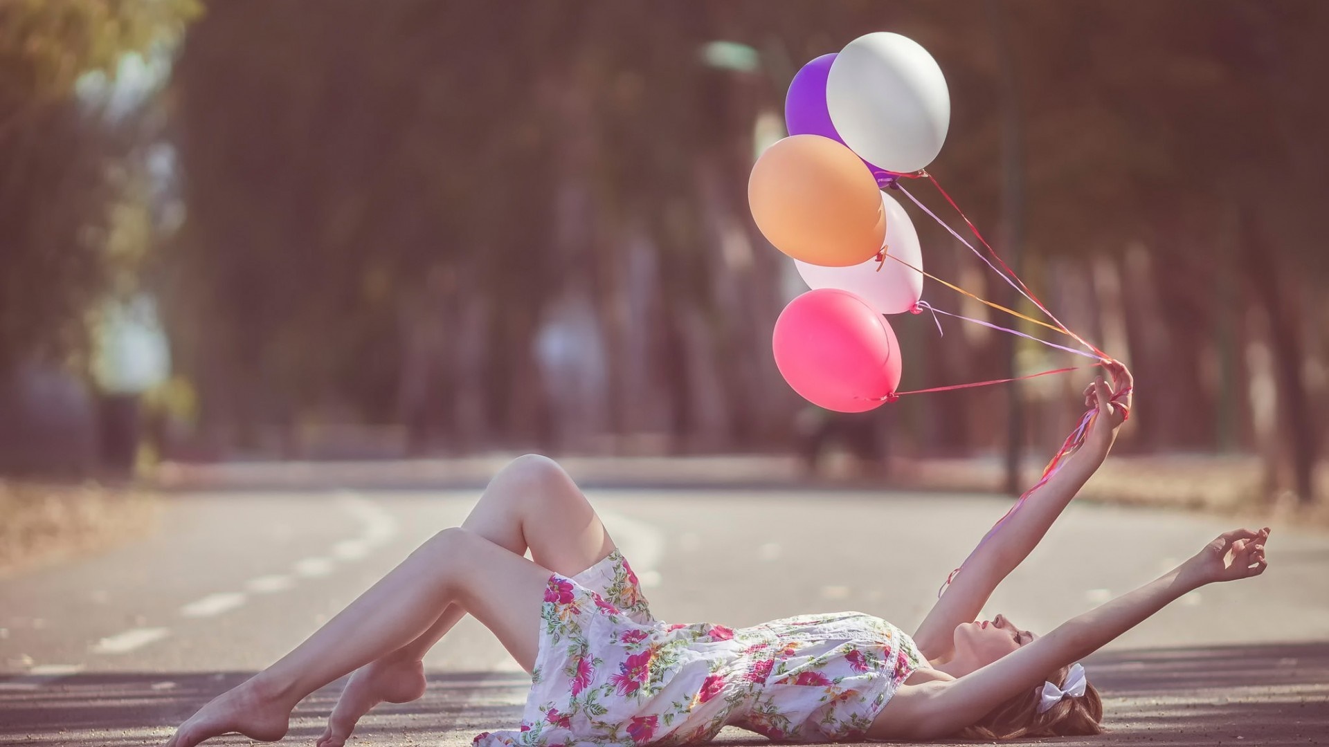 Woman lying on the ground holding balloons HD Wallpaper