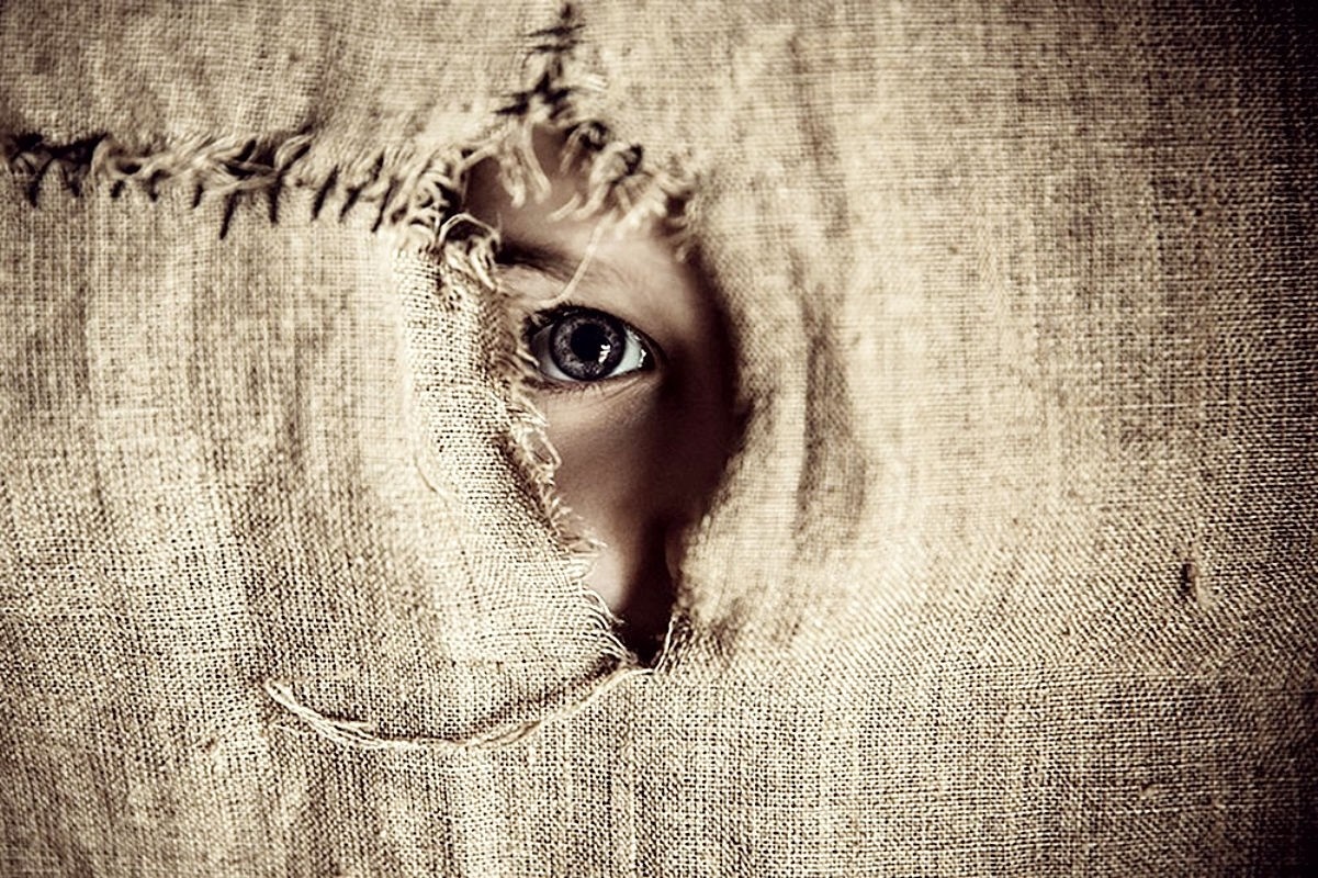 Child's eye peeking through torn burlap fabric HD Wallpaper