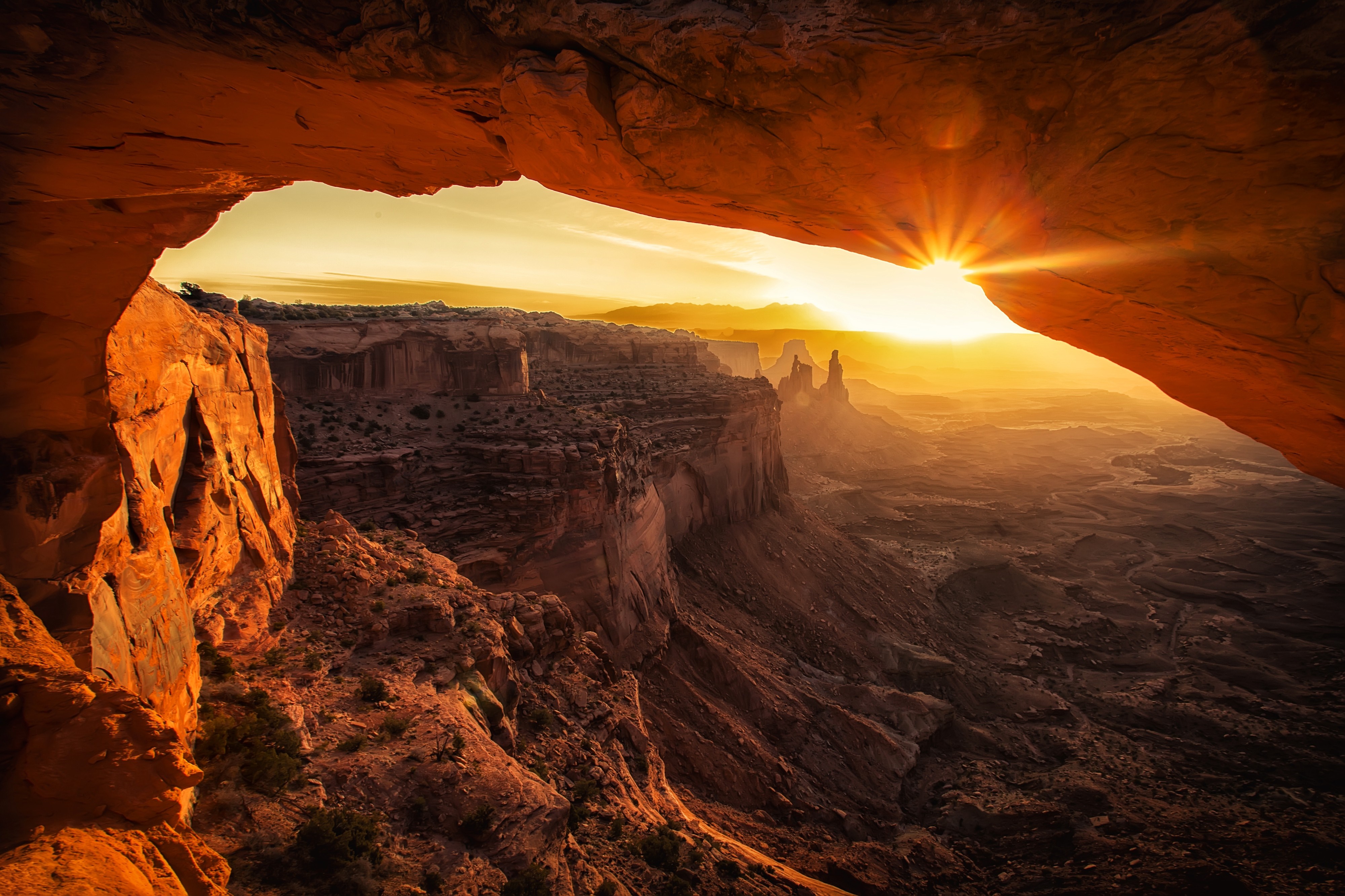 Sunrise viewed through a rock arch in a desert canyon HD Wallpaper