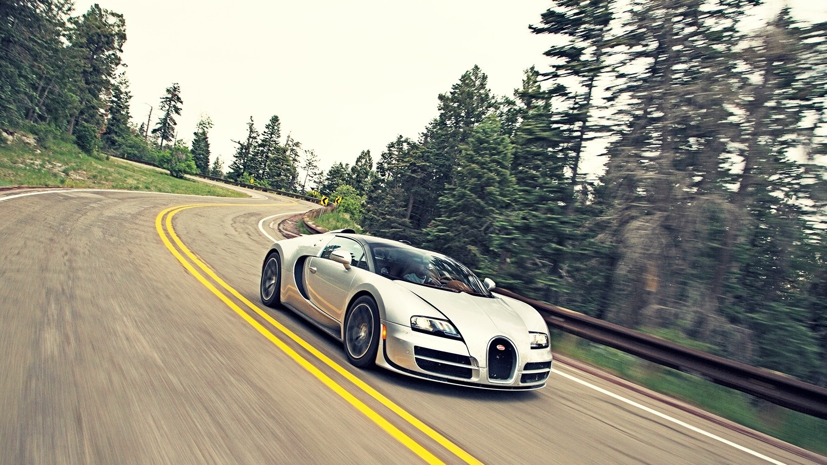 Silver Bugatti Veyron driving on a winding mountain road HD Wallpaper