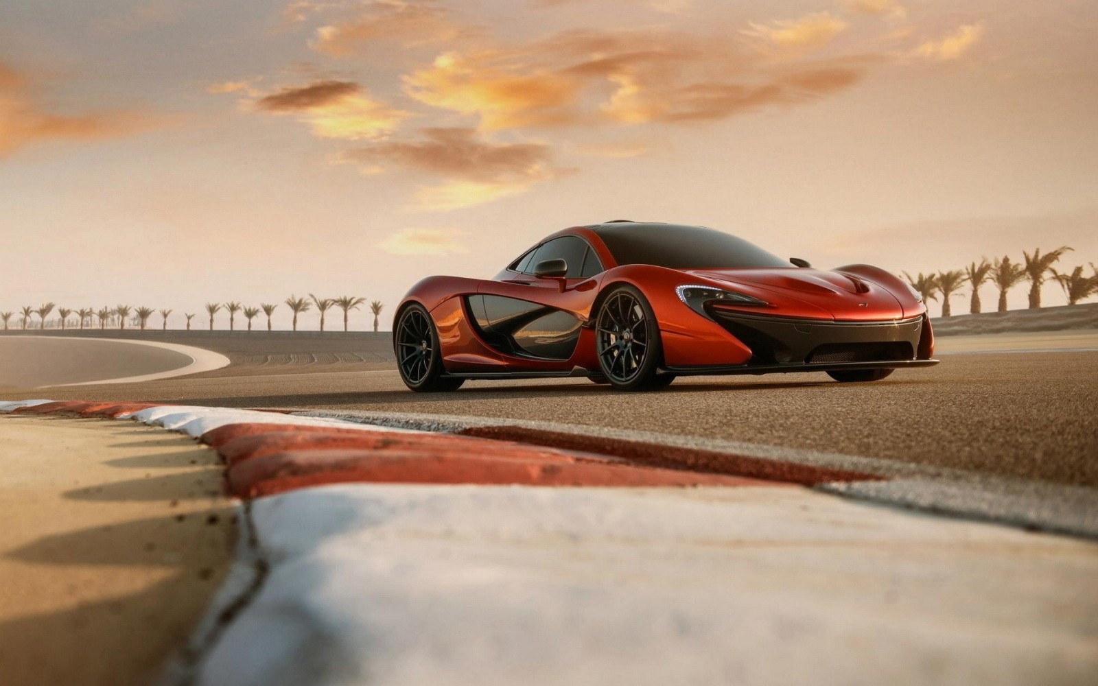 Orange McLaren P1 sports car on a race track HD Wallpaper