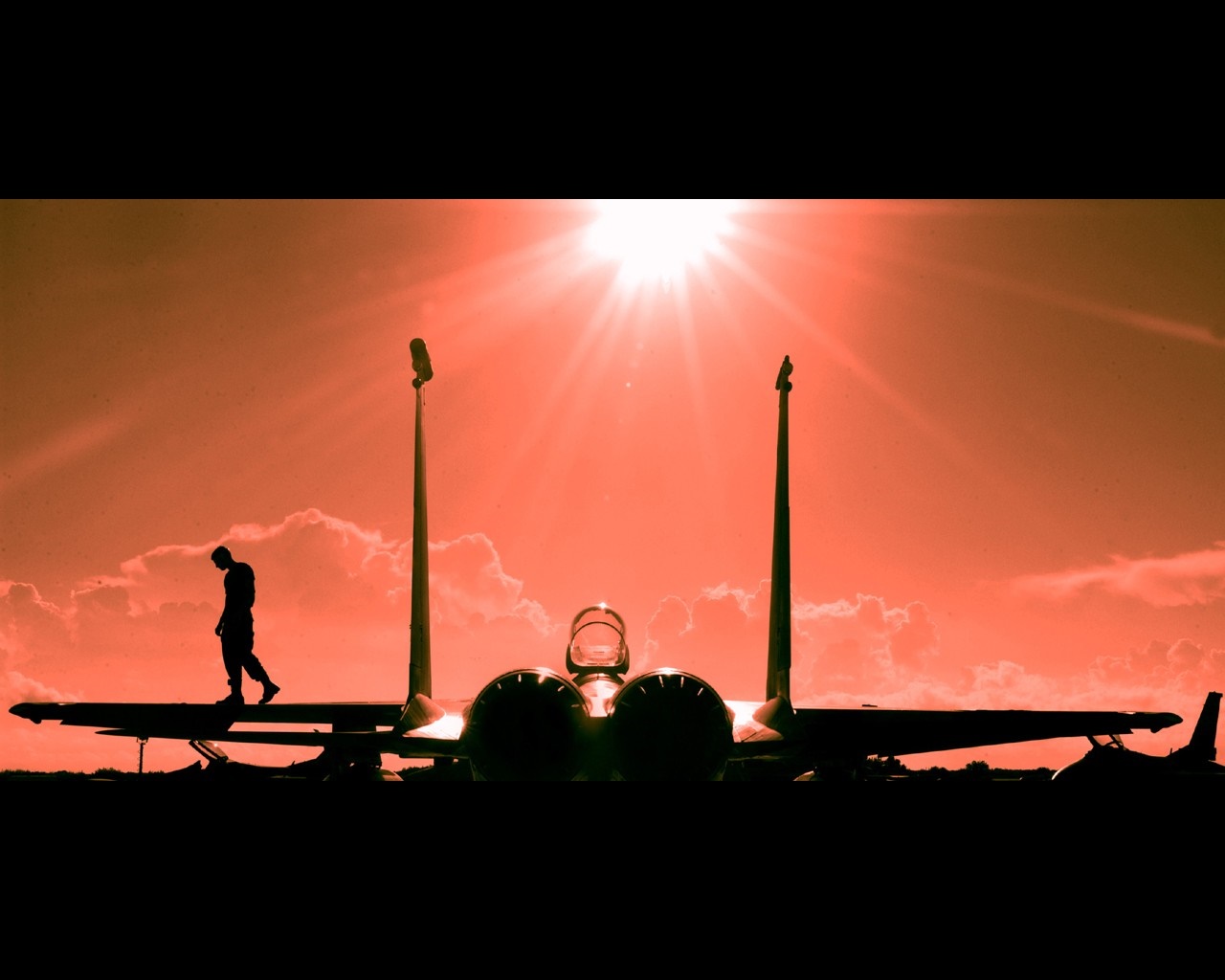 Silhouette of a person walking on a fighter jet at sunset HD Wallpaper