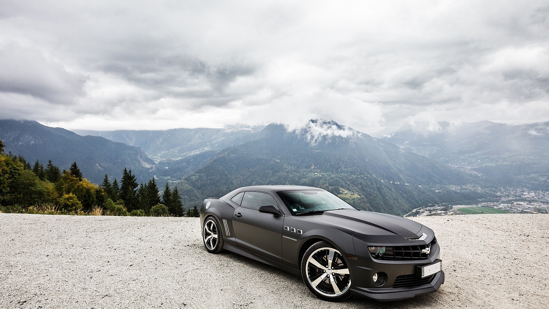 Dark Chevrolet Camaro parked on a gravel road with mountains HD Wallpaper
