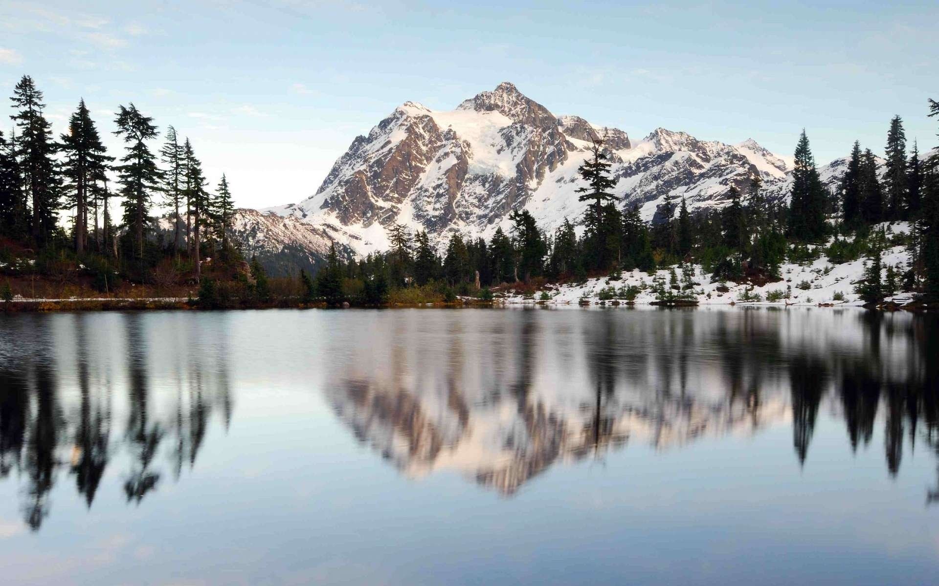 Snow-capped mountain reflected in a lake with pine trees HD Wallpaper
