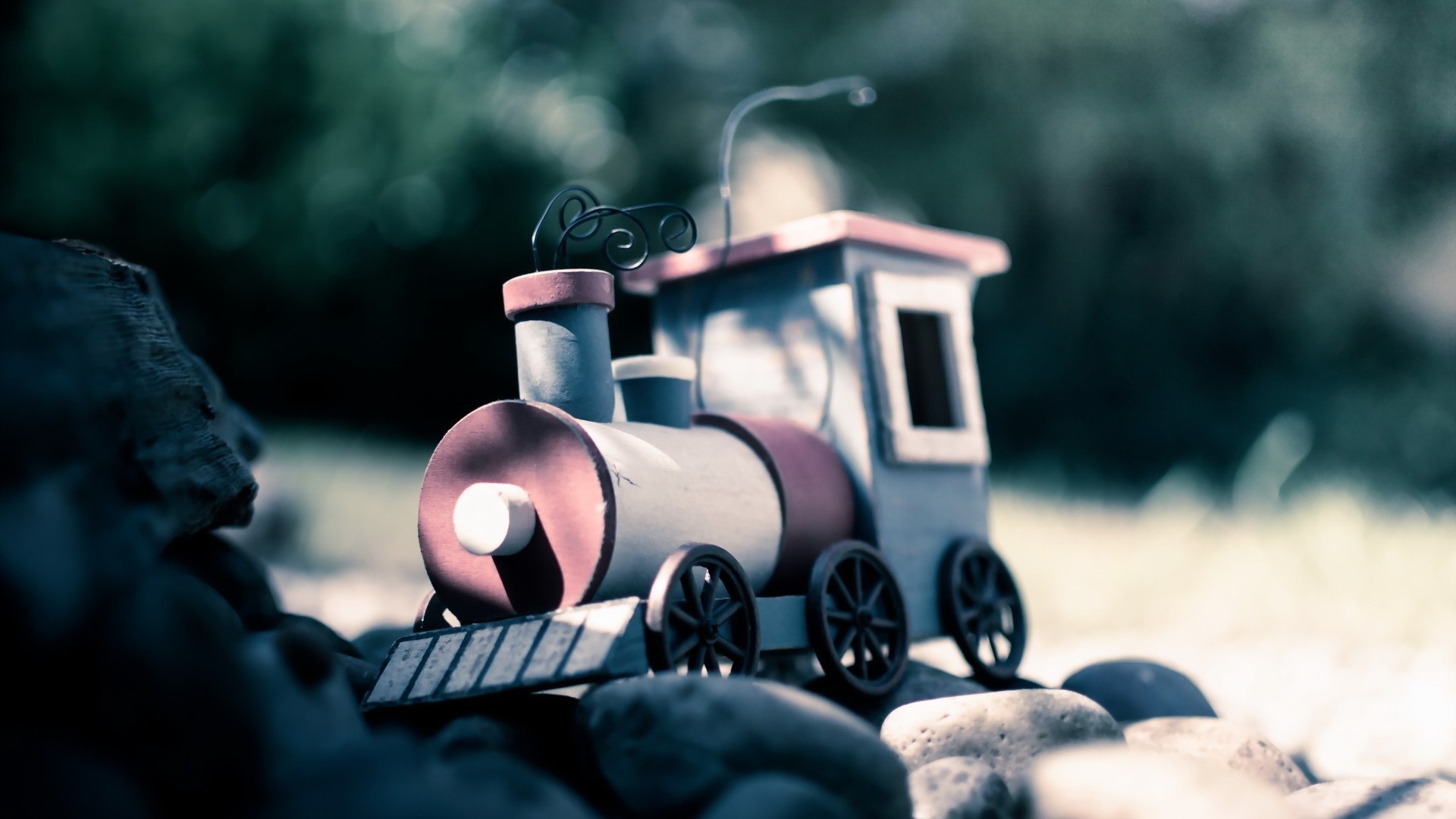 Toy train on rocks with blurred background HD Wallpaper