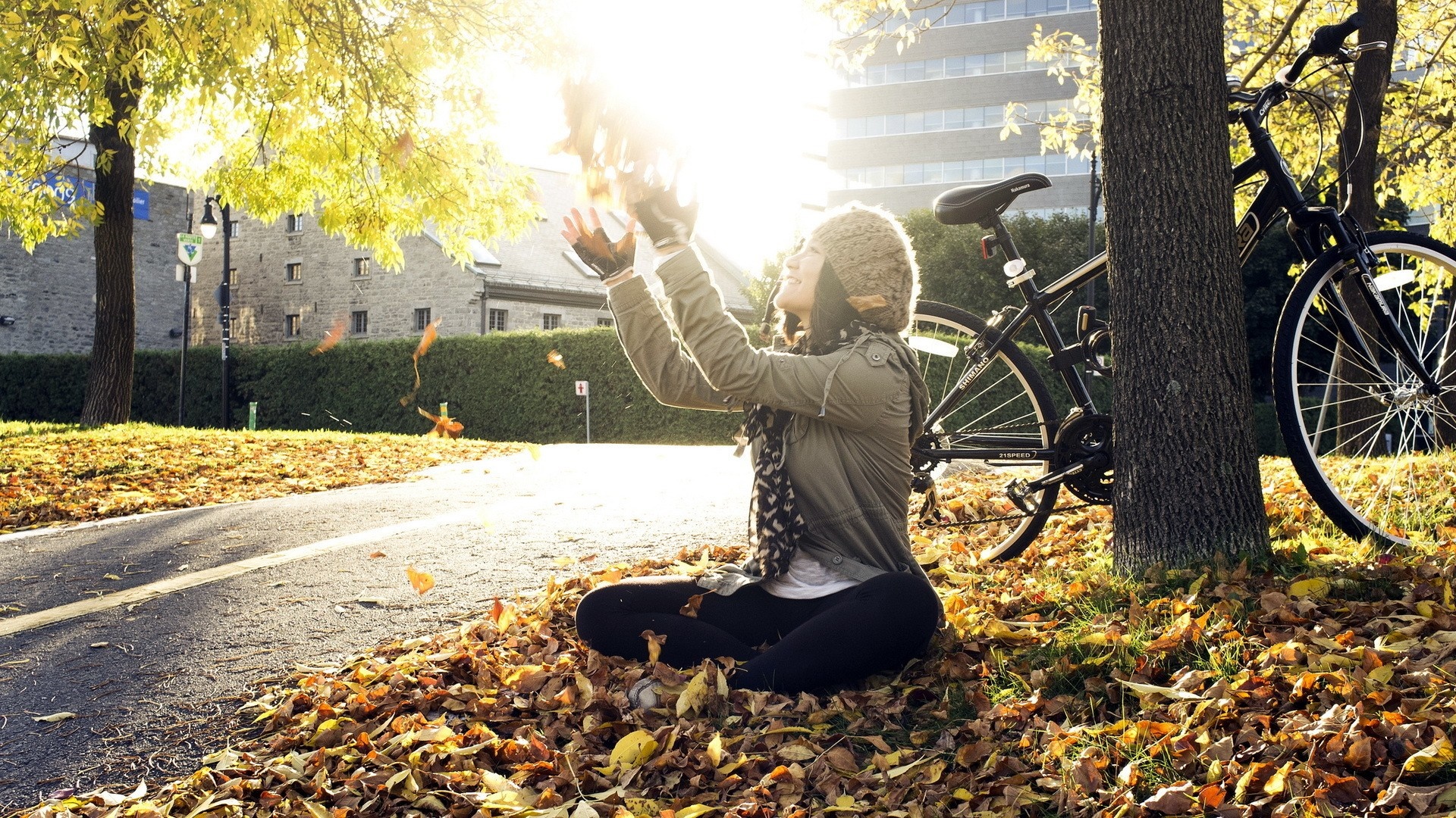 Woman in hat sitting by bicycle in autumn leaves HD Wallpaper