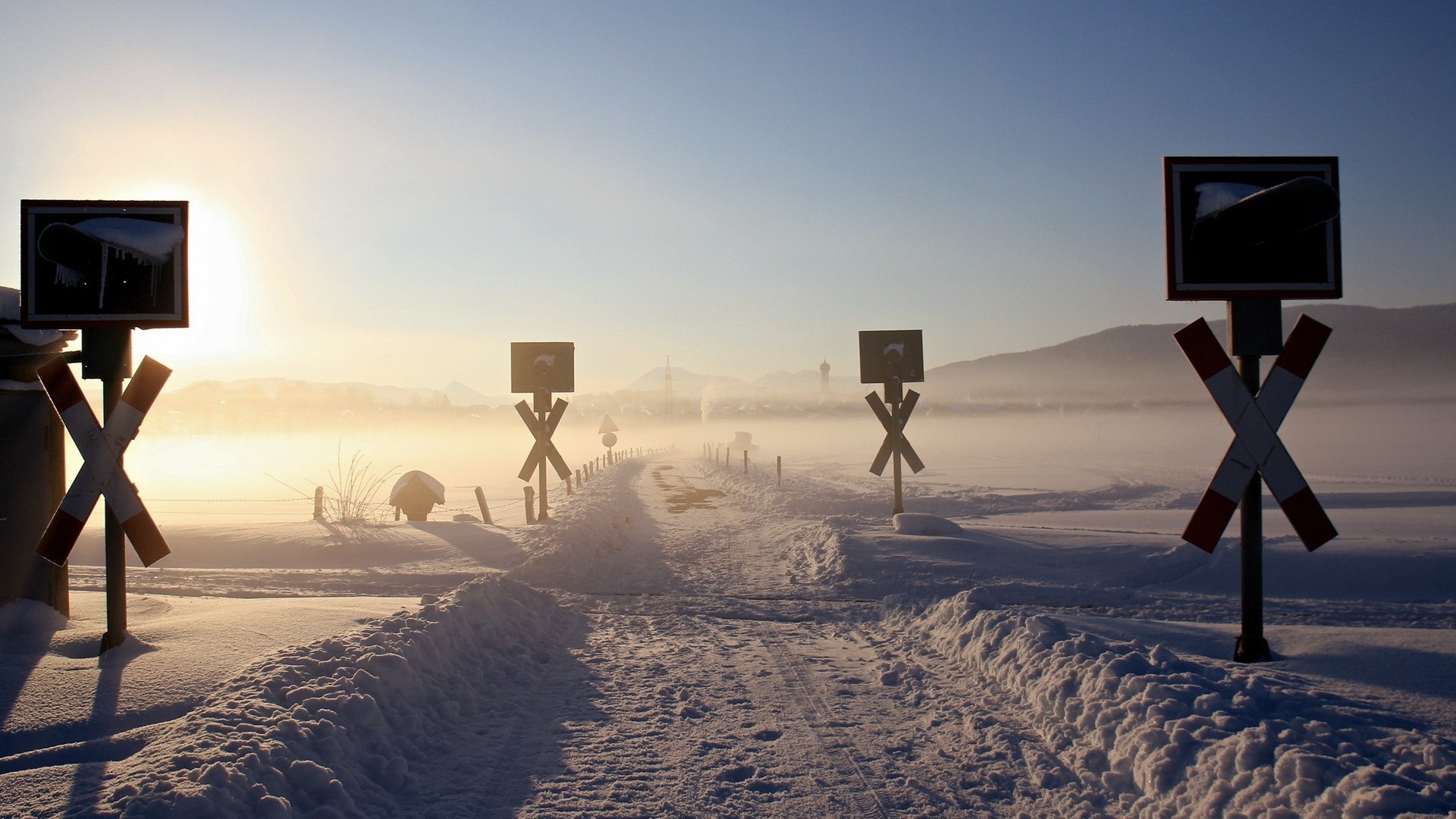 Snowy landscape with railway crossing signs at sunrise HD Wallpaper
