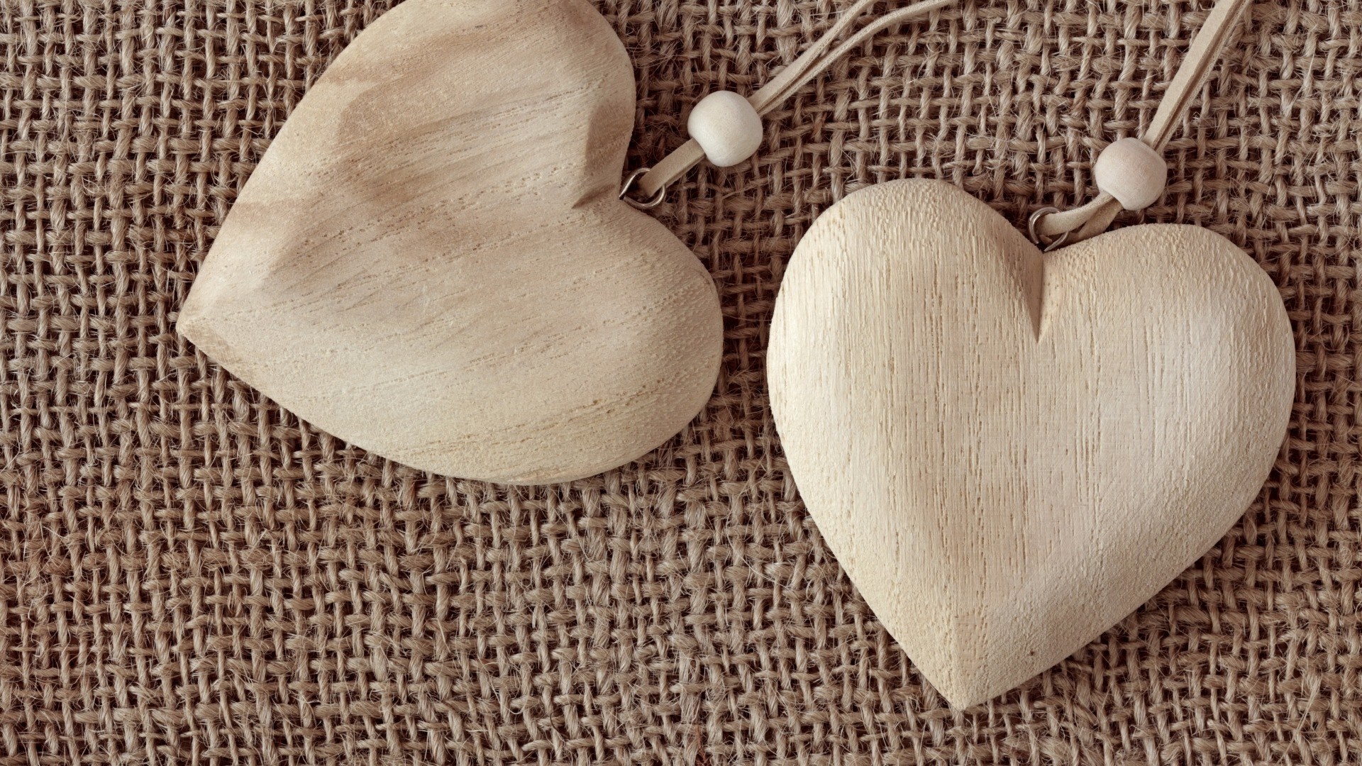 Two wooden heart pendants on burlap HD Wallpaper