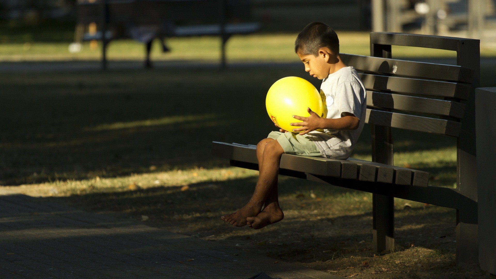 Boy sitting on a park bench with a yellow ball HD Wallpaper