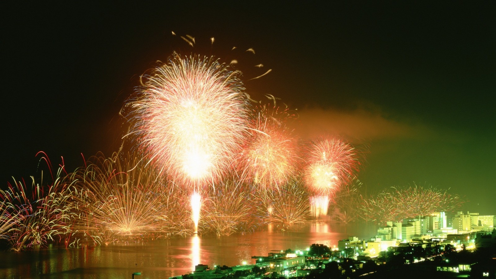 Fireworks display over a city at night HD Wallpaper