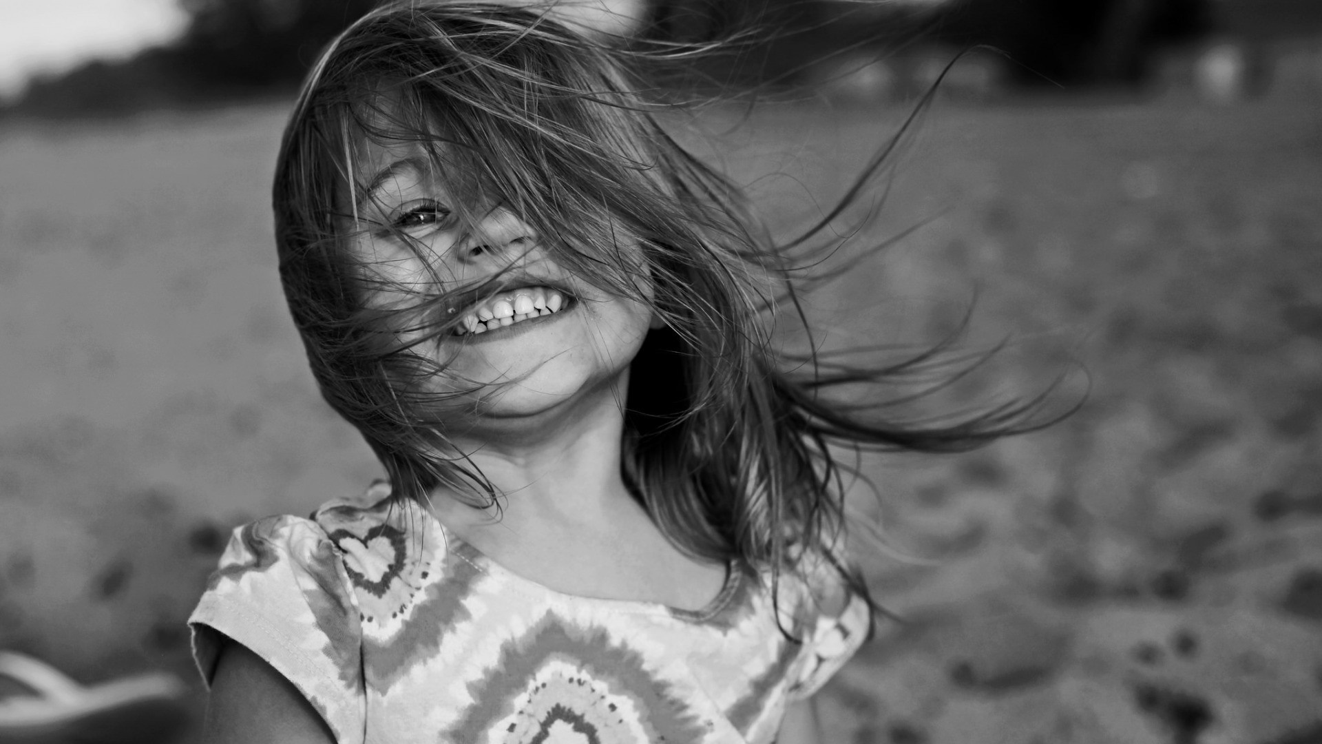 Black and white portrait of a smiling girl with windblown hair HD Wallpaper