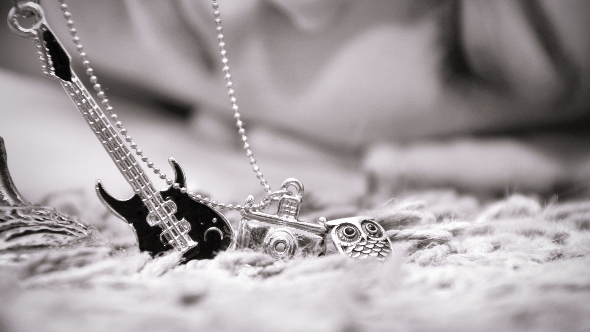 Close up of a silver necklace with charms HD Wallpaper
