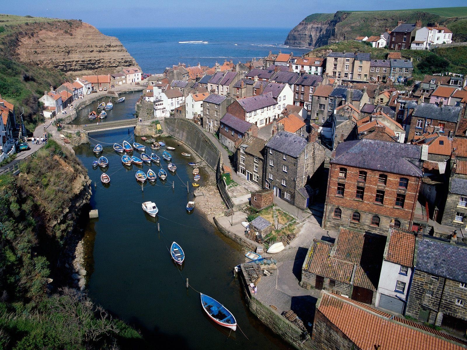 Aerial view of a coastal village with a river and boats HD Wallpaper